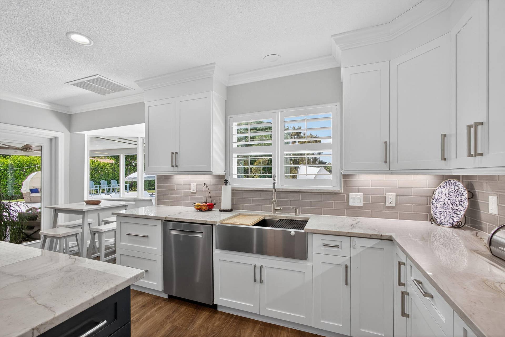 4628 Square Lake Drive, Palm Beach Gardens, FL 33418 Kitchen featuring white shaker-style cabinetry, stone countertops, stainless steel farmhouse sink, subway tile backsplash, and recessed lighting