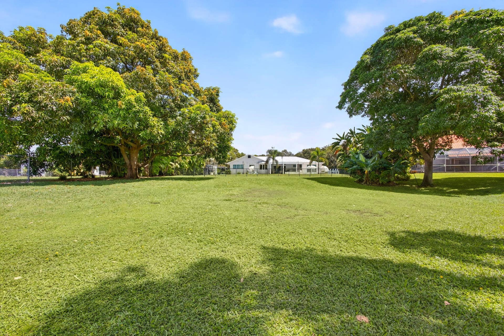 4628 Square Lake Drive, Palm Beach Gardens, FL 33418 Expansive backyard featuring a manicured lawn, established mature trees, and perimeter fencing