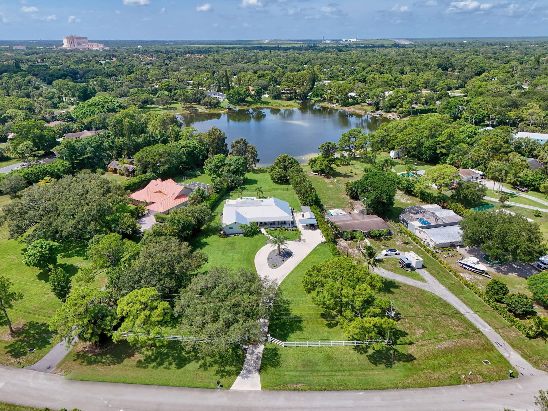 4628 Square Lake Drive, Palm Beach Gardens, FL 33418 Aerial perspective of a sprawling property featuring a multi-gabled residence, a paved circular driveway, expansive manicured grounds, and direct frontage on a private lake