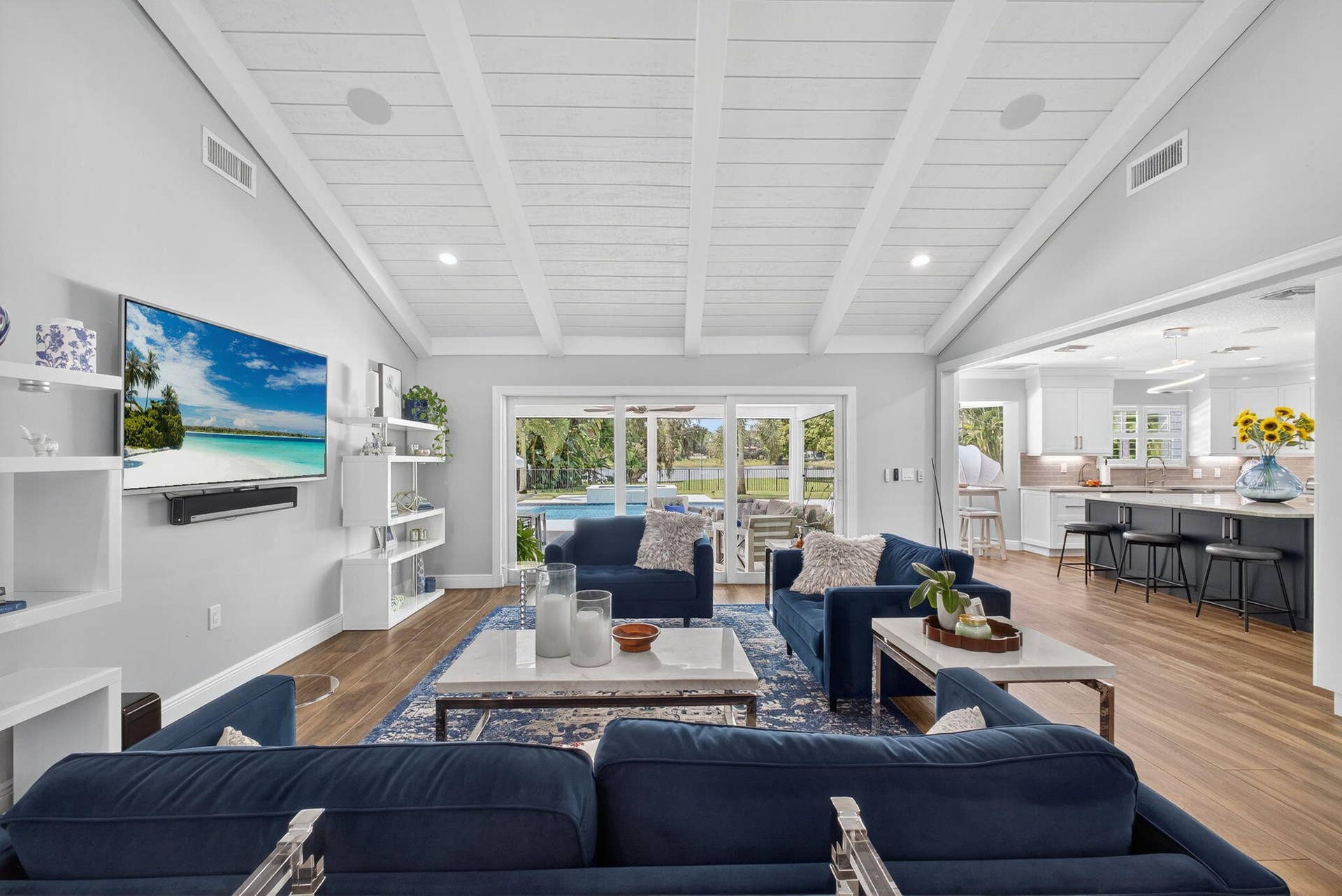 4628 Square Lake Drive, Palm Beach Gardens, FL 33418 Living area featuring a vaulted tongue-and-groove ceiling with exposed beams, wood-finish flooring, built-in shelving, and floor-to-ceiling sliding glass doors