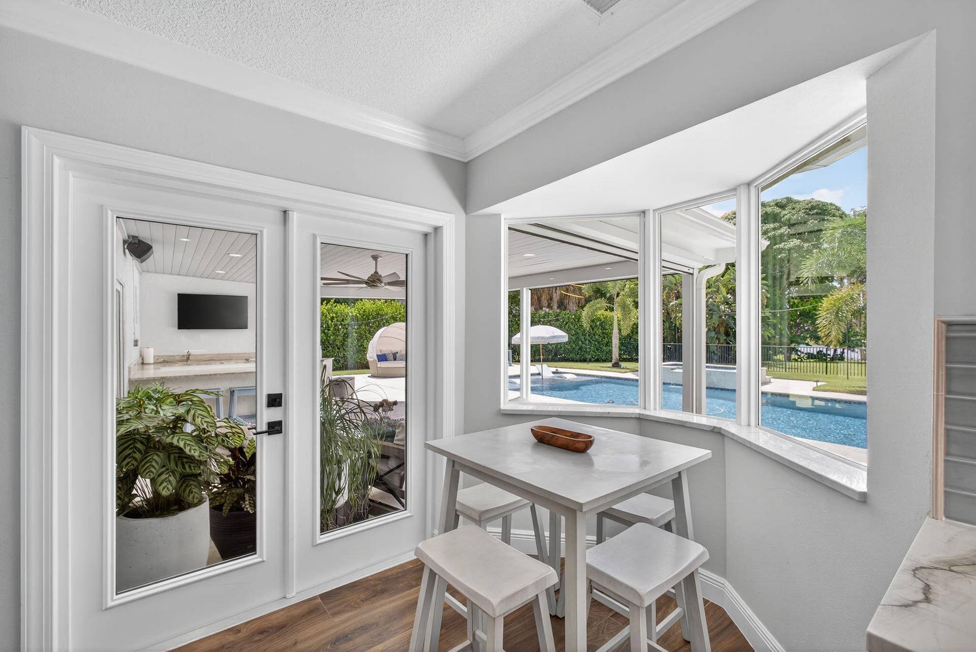 4628 Square Lake Drive, Palm Beach Gardens, FL 33418 Bay window with stone-surfaced ledge, wood-finish flooring, and crown molding, featuring glass-paneled exterior doors