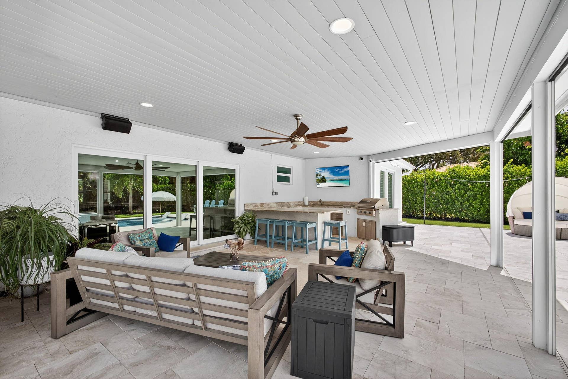 4628 Square Lake Drive, Palm Beach Gardens, FL 33418 Covered outdoor living area featuring a tongue-and-groove ceiling, recessed lighting, ceiling fan, tile flooring, and a built-in outdoor kitchen with stone-finish countertops