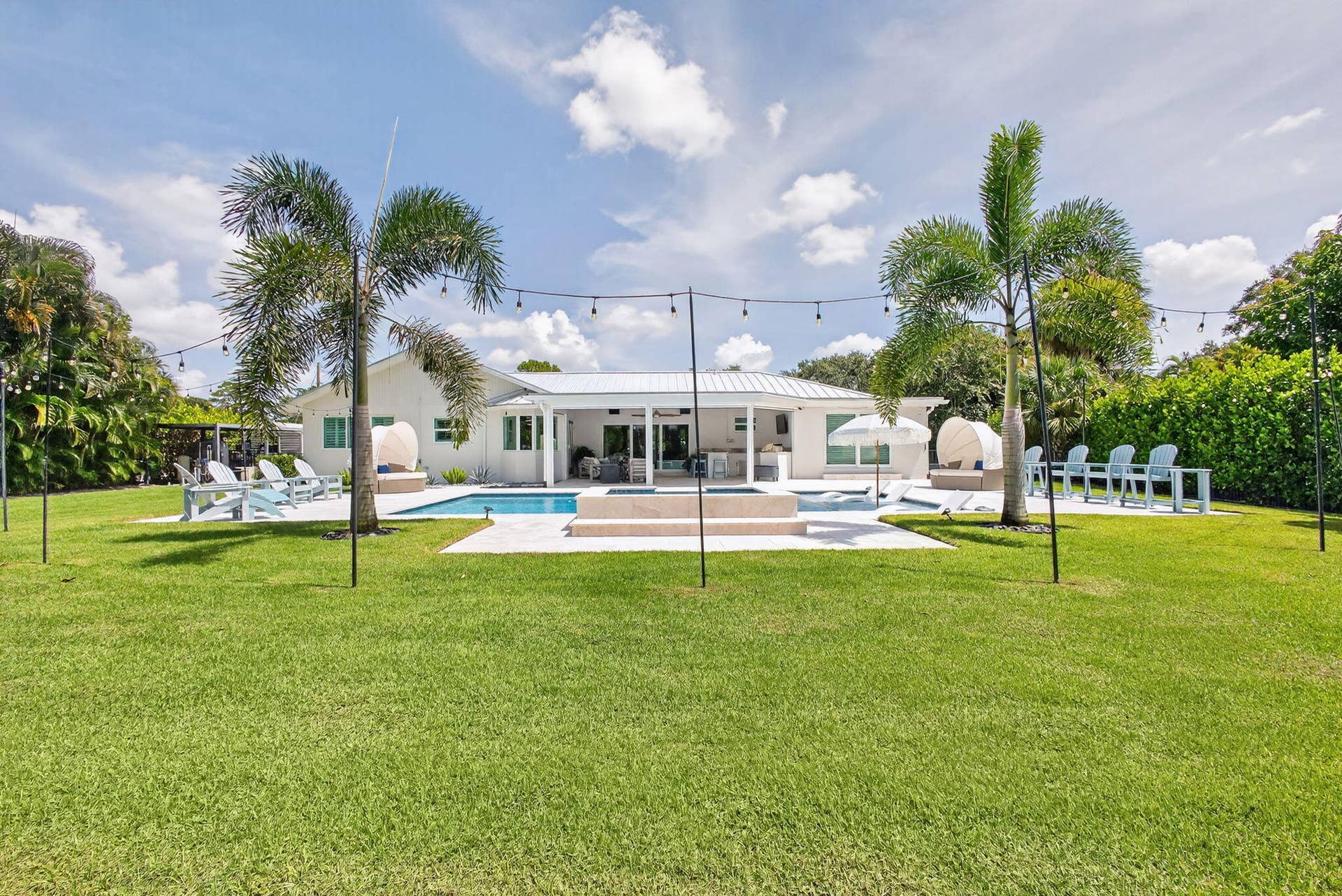 4628 Square Lake Drive, Palm Beach Gardens, FL 33418 Expansive backyard featuring a swimming pool, stone-paver patio, covered porch, and mature palm trees