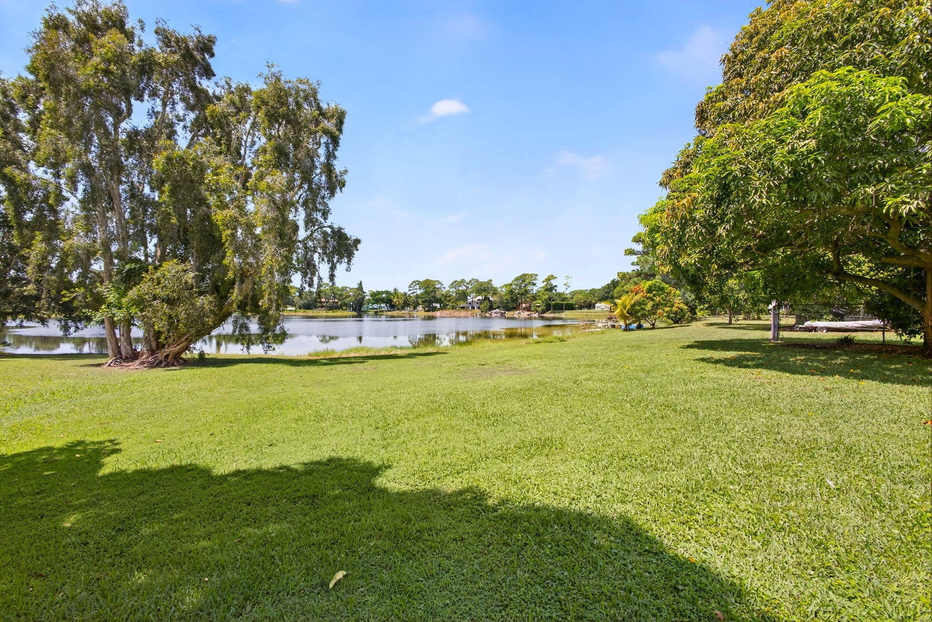 4628 Square Lake Drive, Palm Beach Gardens, FL 33418 Expansive grassy lawn featuring mature trees and direct waterfront frontage