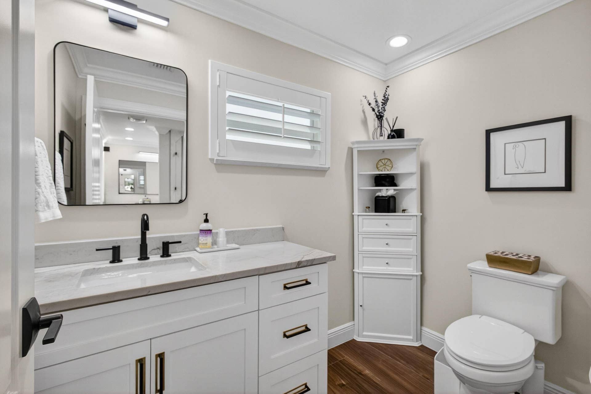 4628 Square Lake Drive, Palm Beach Gardens, FL 33418 White vanity with stone countertop, matte black widespread faucet, rectangular undermount sink, built-in corner cabinetry, and wood-finish flooring