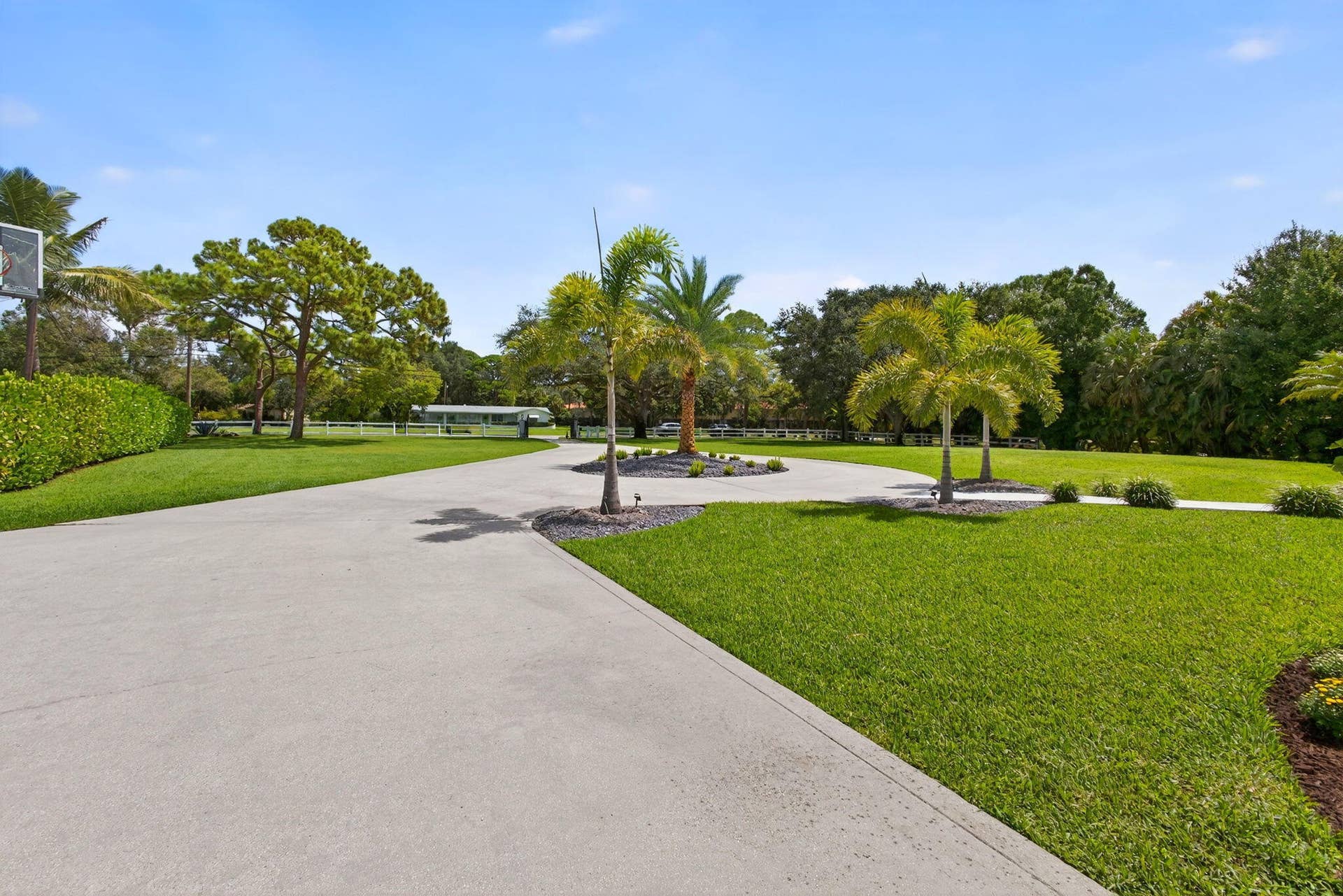 4628 Square Lake Drive, Palm Beach Gardens, FL 33418 Extensive concrete driveway, landscaped grounds with mature palm trees, manicured turf, and decorative stone-mulched garden beds