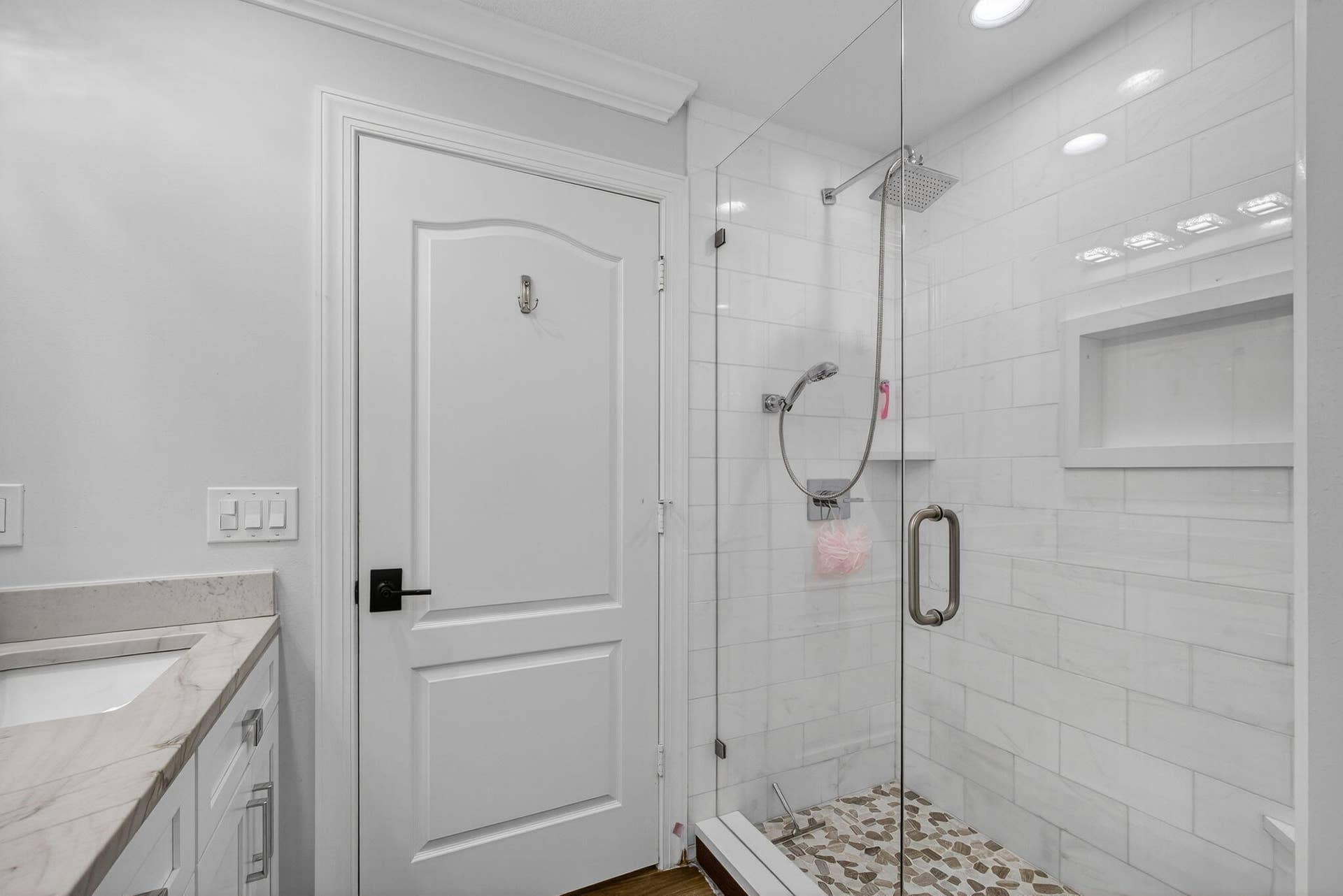 4628 Square Lake Drive, Palm Beach Gardens, FL 33418 Bathroom featuring a walk-in shower with glass enclosure, subway tile surround, built-in recessed shelf, stone-finish flooring, and vanity with stone countertop