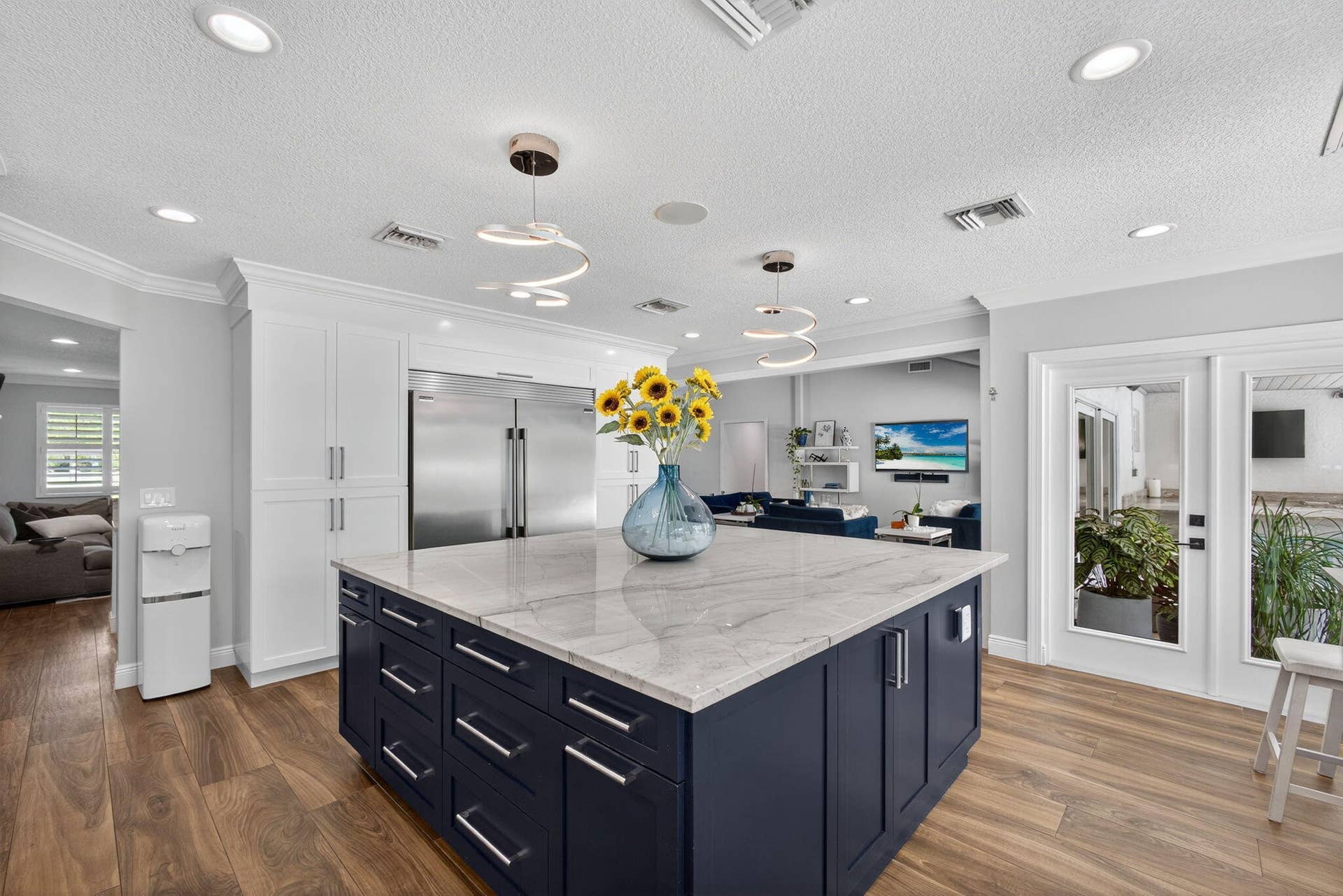 4628 Square Lake Drive, Palm Beach Gardens, FL 33418 Kitchen featuring a large central island with a stone countertop, navy blue custom cabinetry, stainless steel refrigerator, recessed lighting, and wood-finish flooring