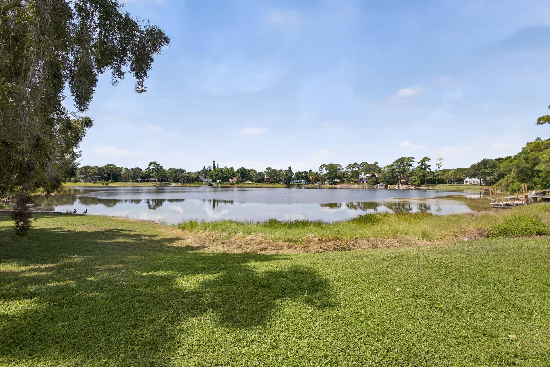 4628 Square Lake Drive, Palm Beach Gardens, FL 33418 Expansive waterfront lot featuring mature trees, manicured lawn, and direct shoreline access