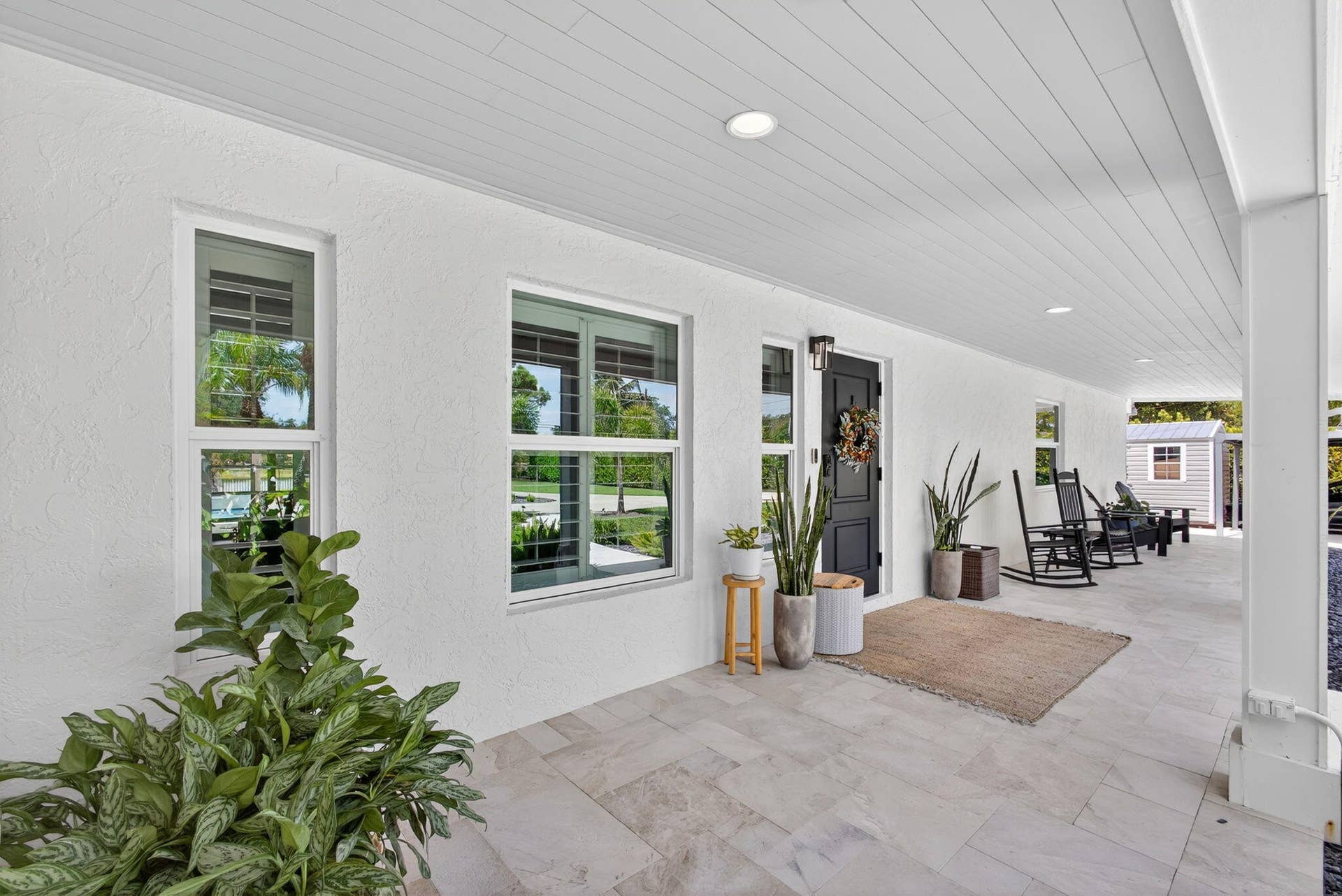 4628 Square Lake Drive, Palm Beach Gardens, FL 33418 Covered front porch featuring large-format tile flooring, beadboard ceiling, recessed lighting, and a dark-toned entry door
