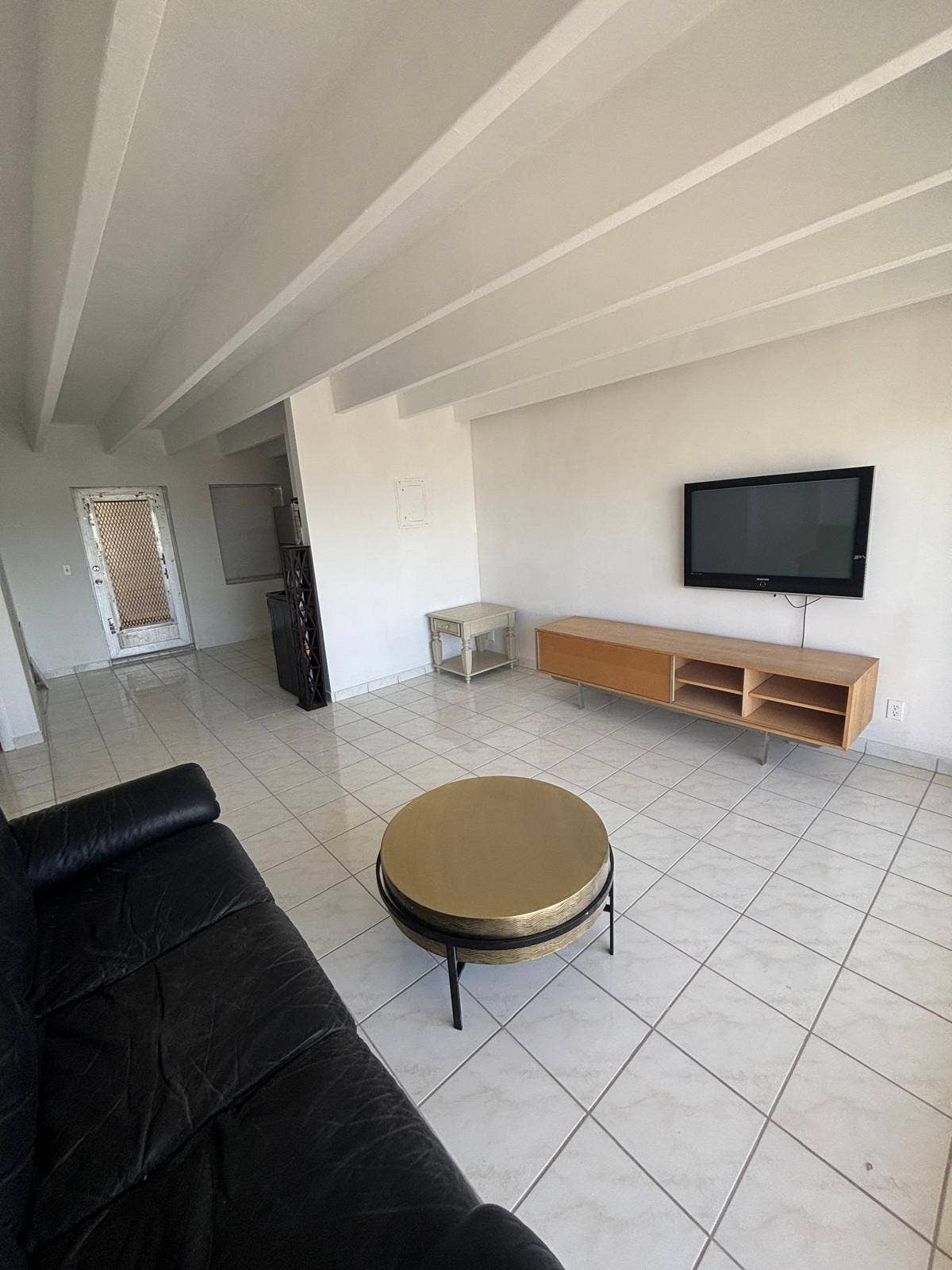 4500 S Ocean Boulevard, #310, South Palm Beach, FL 33480 Open-concept space featuring high exposed-beam ceilings, polished ceramic tile flooring, and a mounted media cabinet