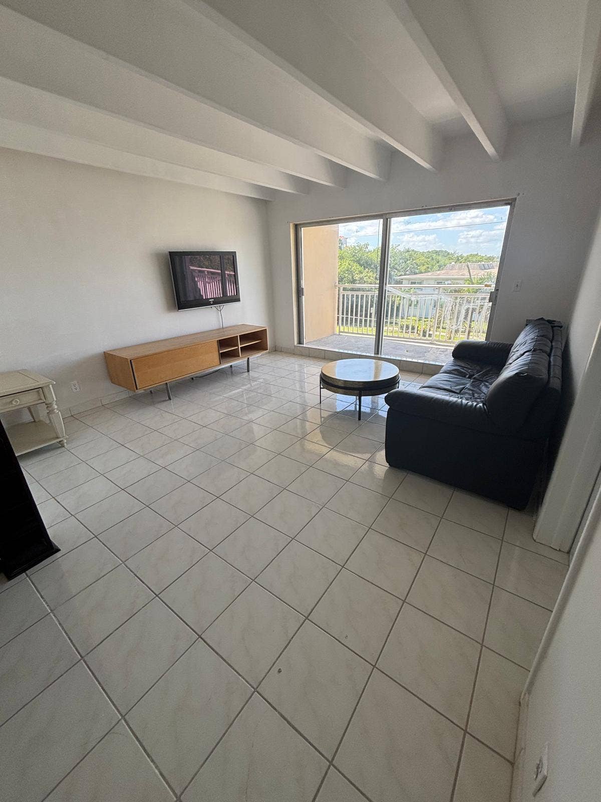 4500 S Ocean Boulevard, #310, South Palm Beach, FL 33480 Living area featuring a vaulted ceiling with exposed beams, ceramic tile flooring, and a sliding glass door providing external access