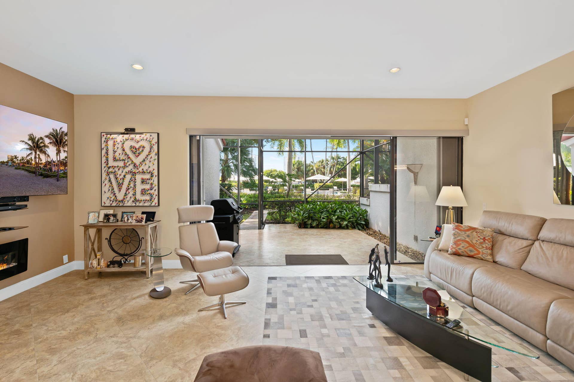 Open-concept room featuring an electric fireplace, large-format tile flooring, and retractable sliding glass doors opening to a screened lanai