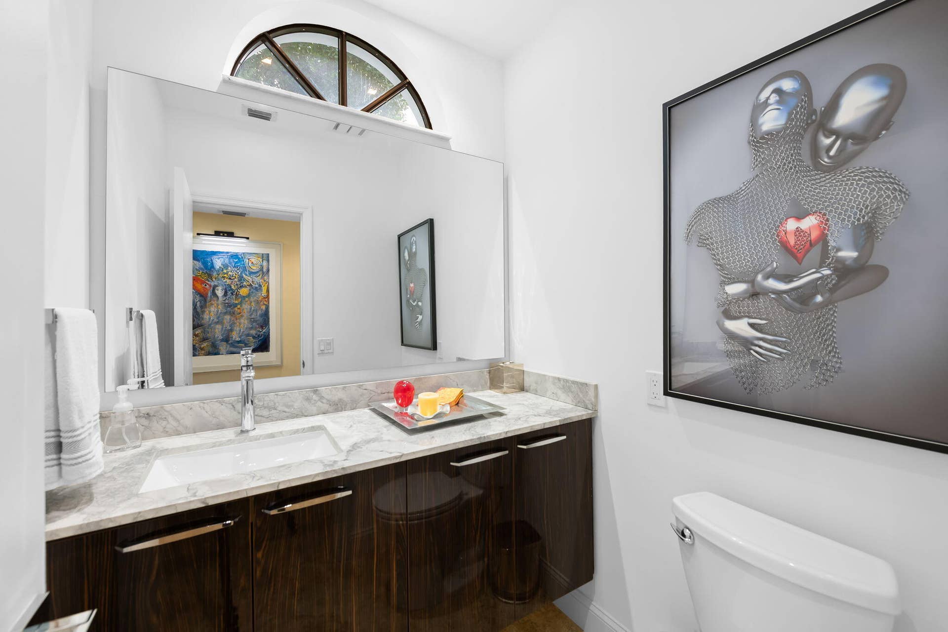 Floating vanity with dark wood-finish cabinetry, stone countertop, integrated rectangular sink, and large frameless mirror