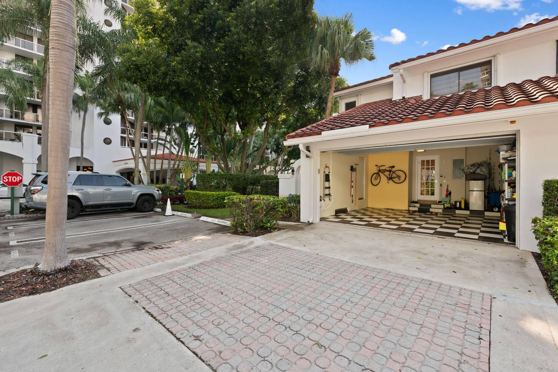 Attached garage with checkered flooring, paver driveway, terracotta roof tiles, and exterior stucco finish