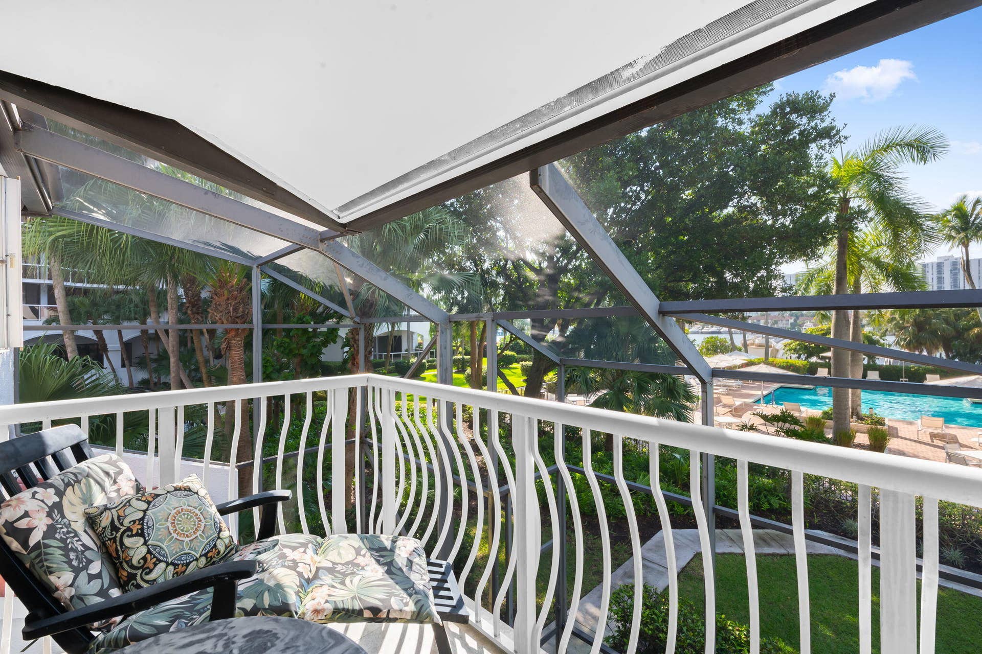 Screened-in balcony in primary bedroom featuring a white metal railing and a solid roof covering