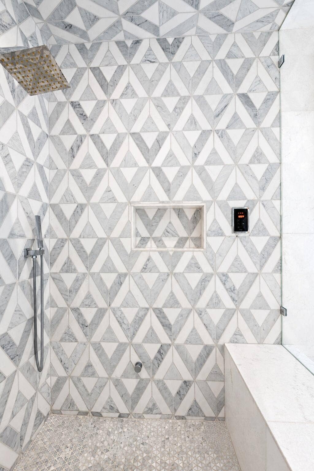 Glass enclosed walk in steam shower with geometric patterned tile and bench seating. Newly remodeled