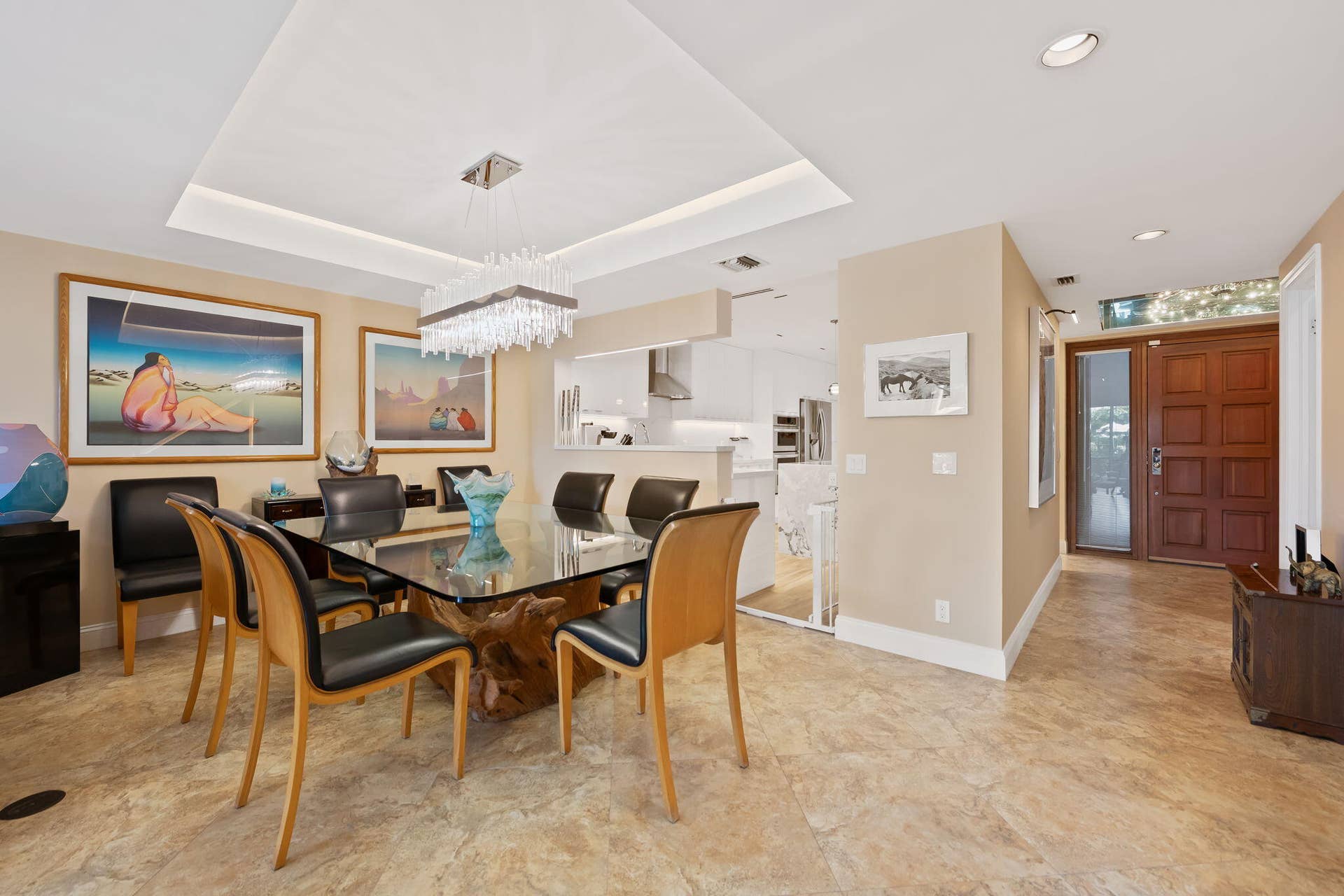 Open-concept interior featuring stone-finish flooring, a recessed tray ceiling, a multi-paneled wood entry door with glass transom