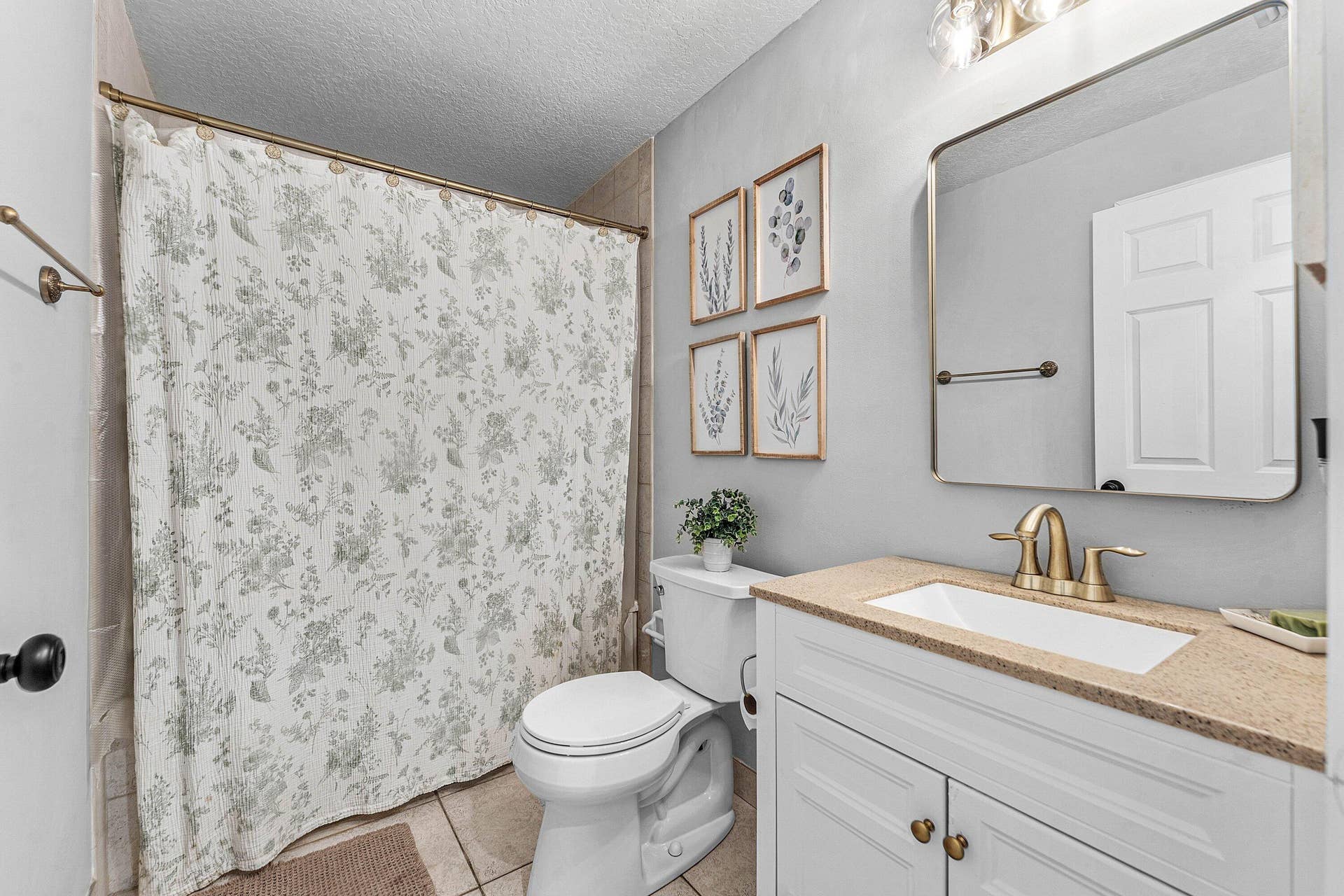 Bathroom featuring a vanity with white cabinetry, a neutral countertop, an integrated rectangular sink, a metallic faucet, and a large rectangular mirror with metallic framing