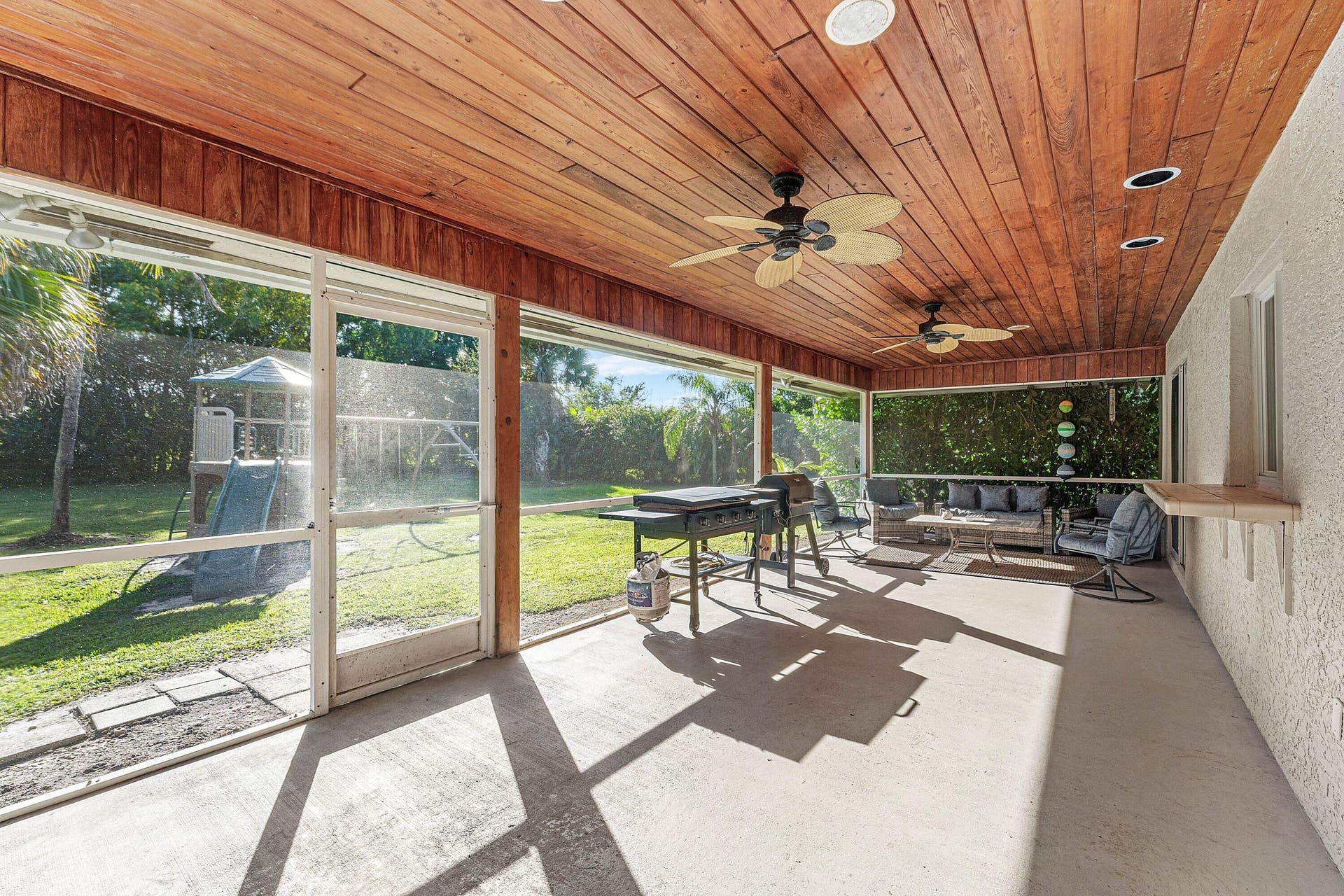 Screened-in patio featuring a wood-plank ceiling, recessed lighting, ceiling fans, and a built-in wall shelf