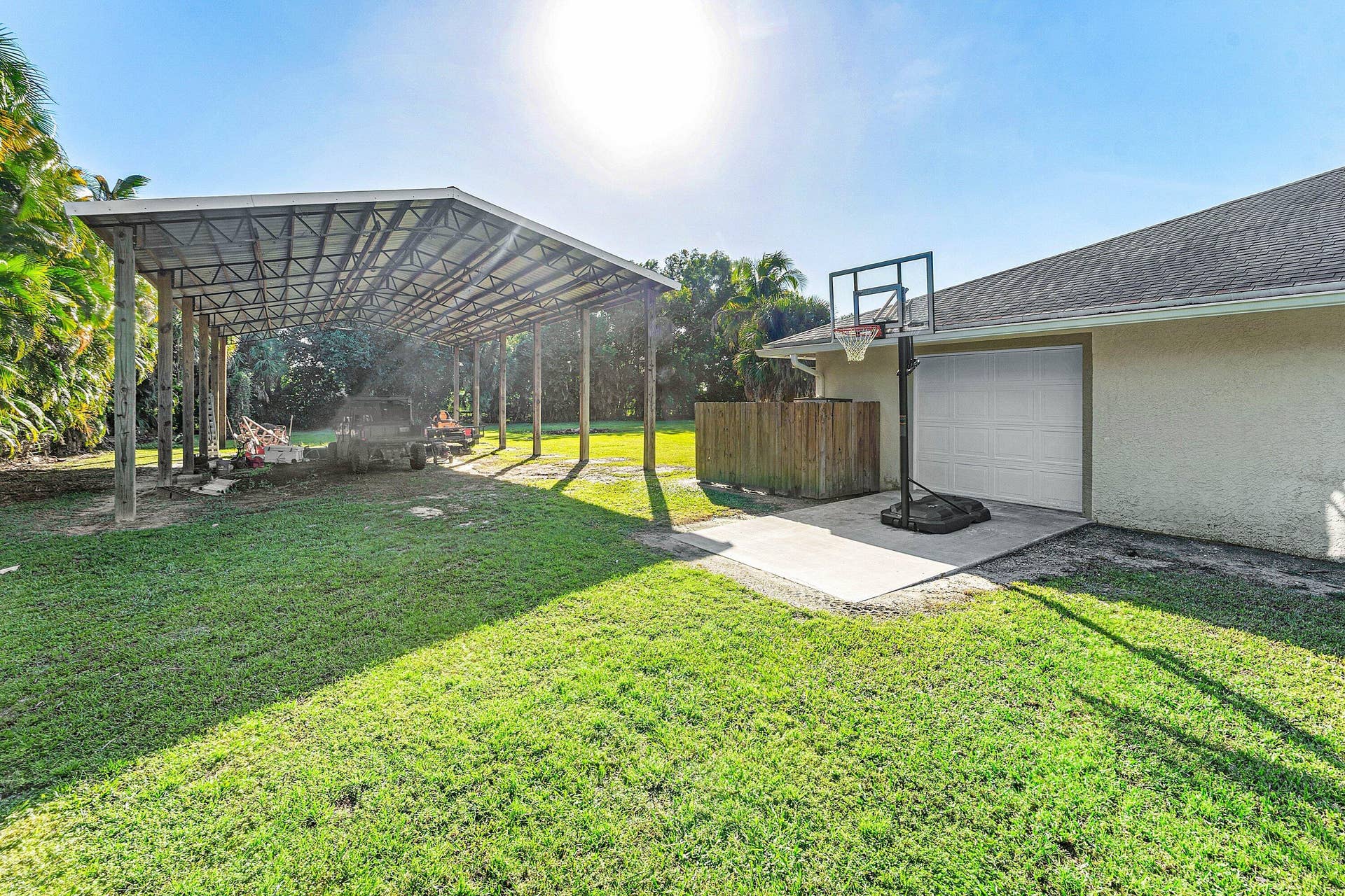 Exterior space featuring an expansive covered carport, a concrete pad, a garage, and a grass lawn
