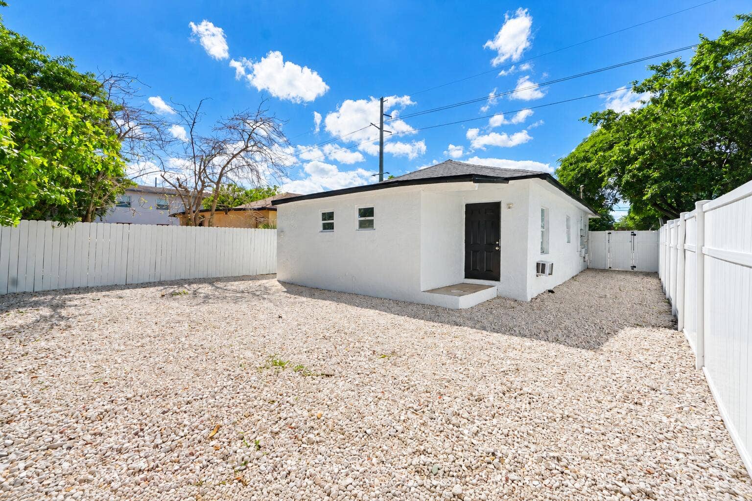 Sunlit Gravel Yard and White Stucco Hous