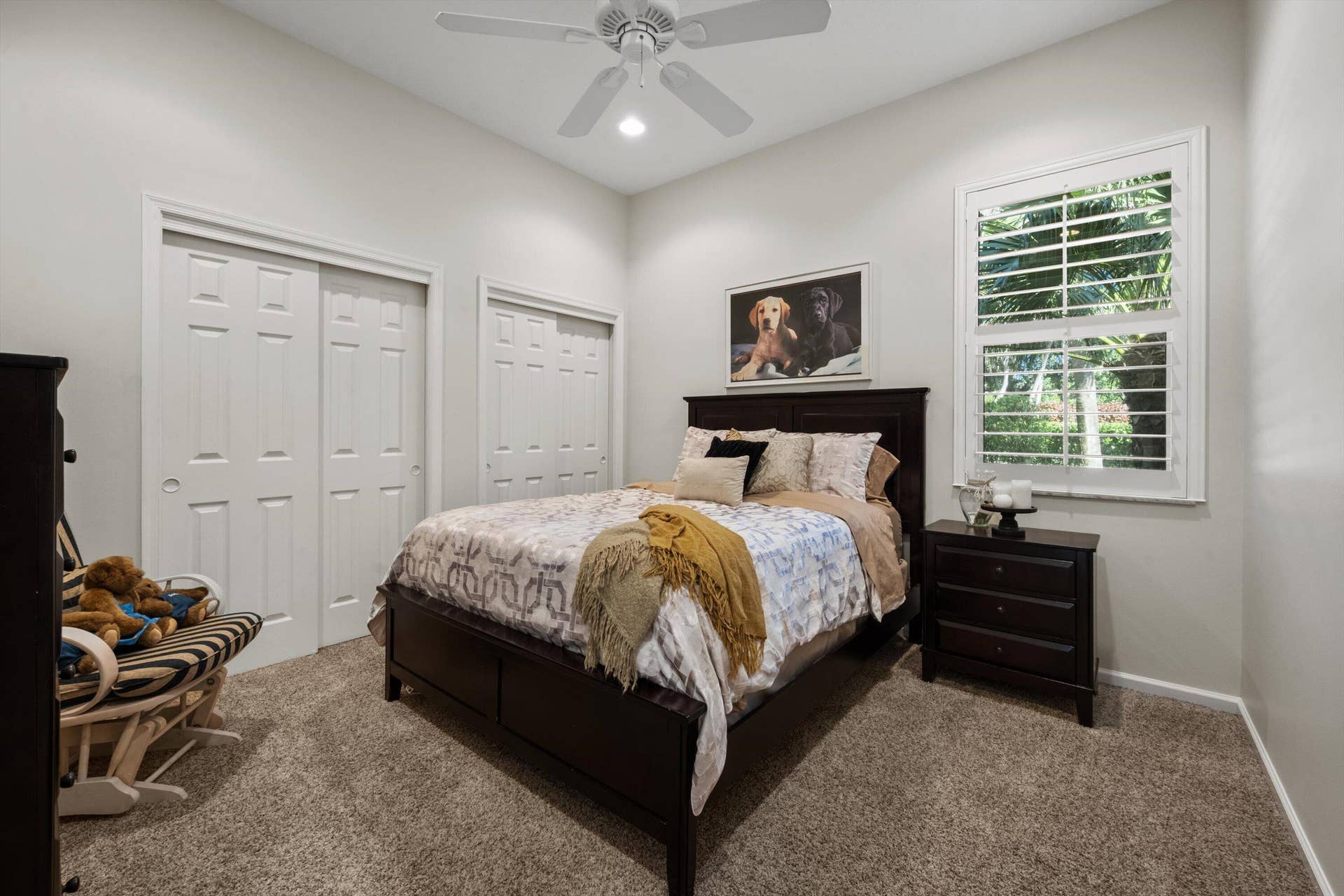 High-ceiling room featuring neutral carpeting, plantation shutter window coverings, and a ceiling-mounted fan with integrated lighting