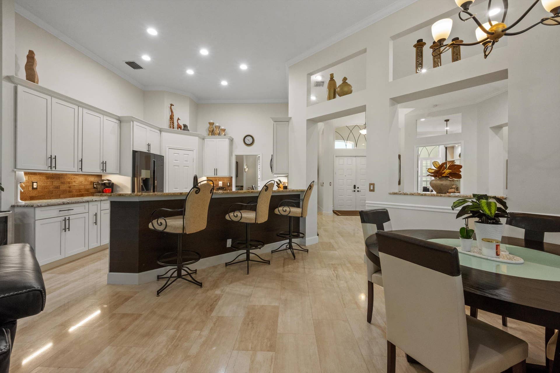 Kitchen featuring shaker-style cabinetry, stone countertops, a raised breakfast bar, recessed lighting, and tile flooring