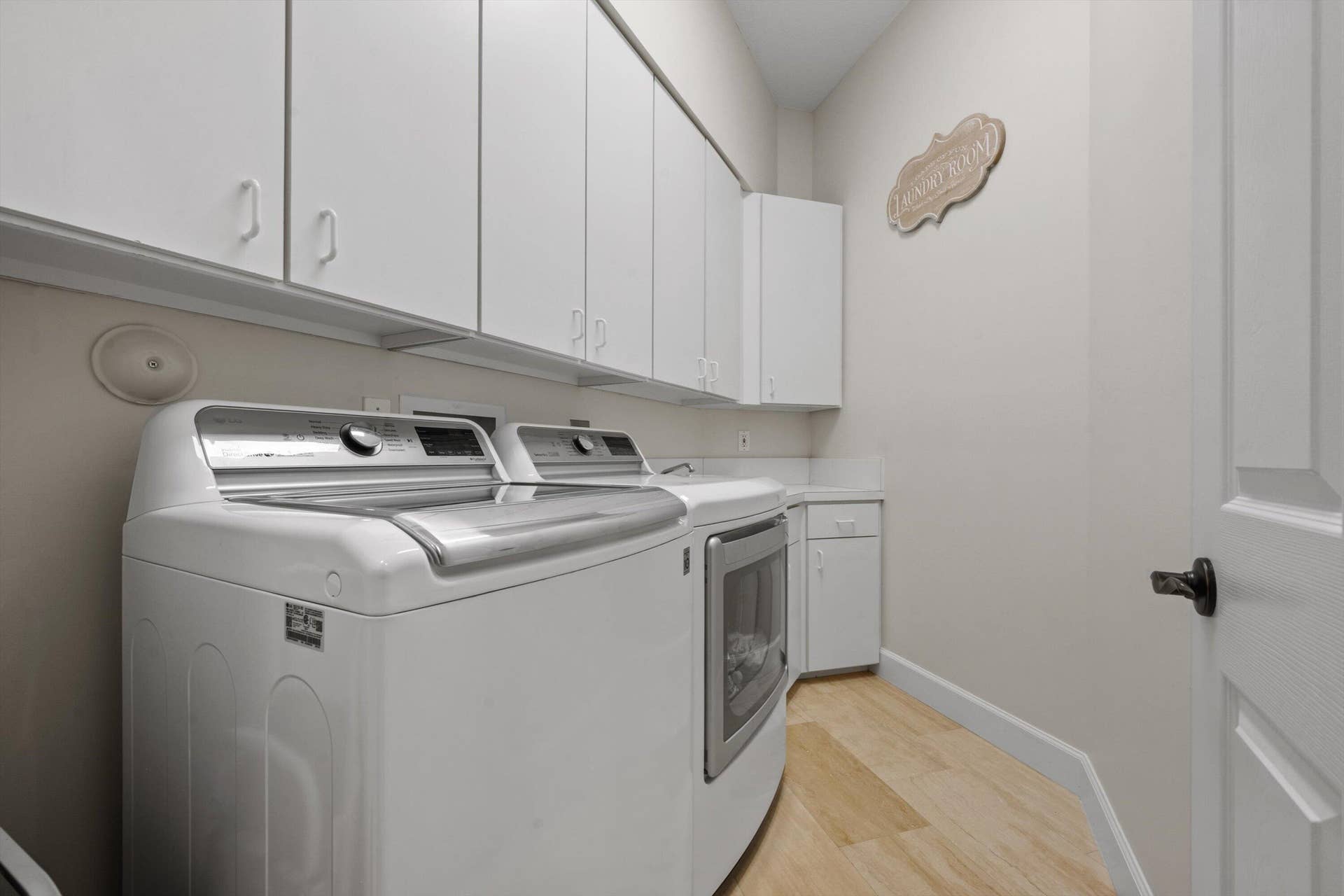 Laundry area featuring extensive upper cabinetry, base cabinet storage, and wood-finish flooring