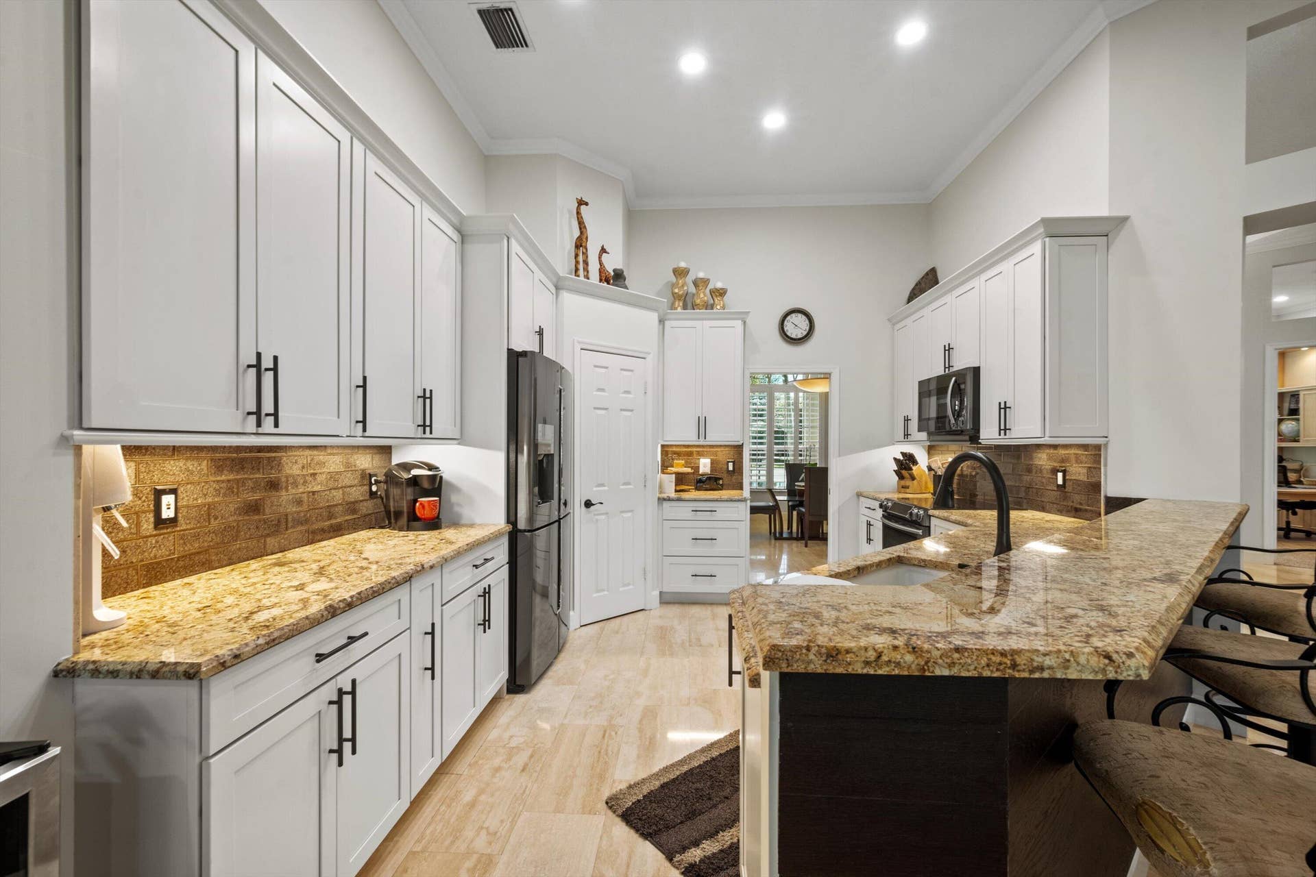 Kitchen featuring white cabinetry with matte black hardware, stone-finish countertops, tile backsplash, and recessed lighting