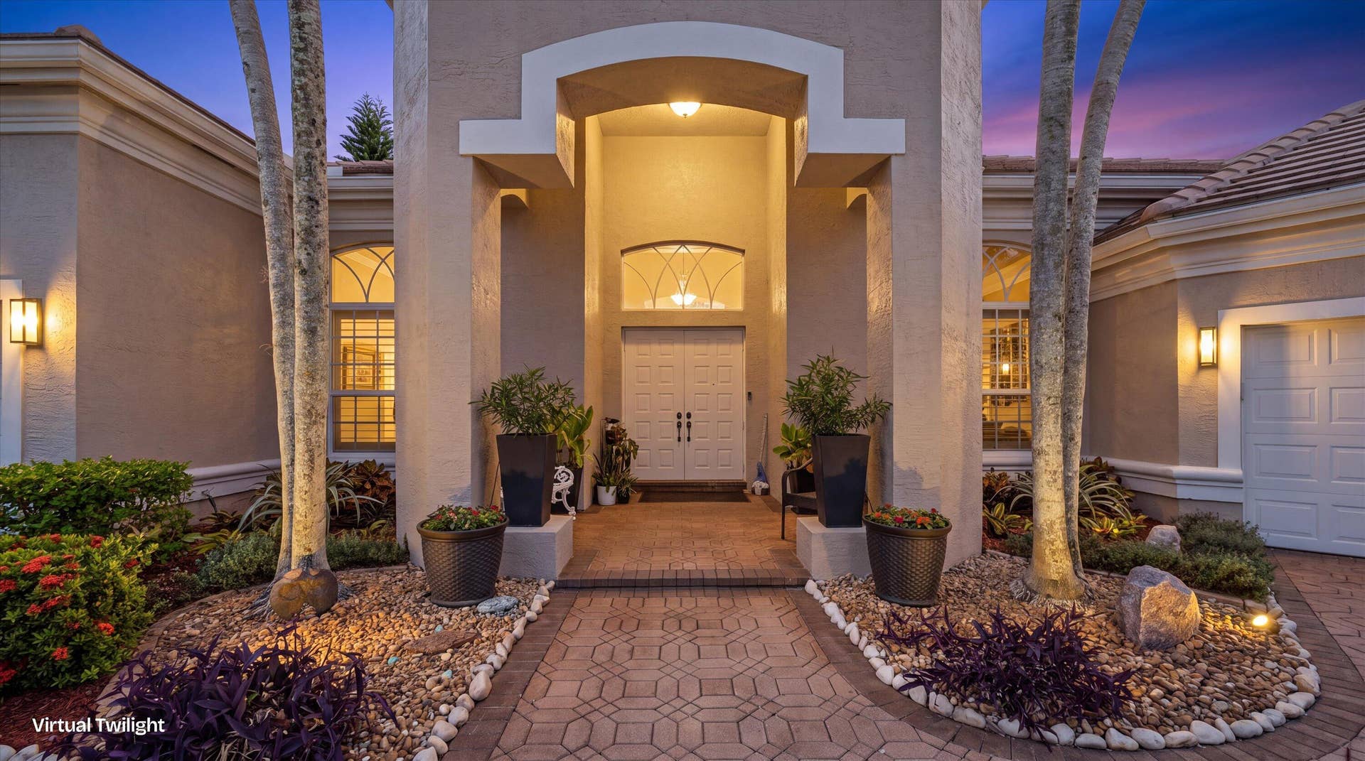 Stucco exterior featuring an arched entryway, double-door entrance, transom window, and paver walkway