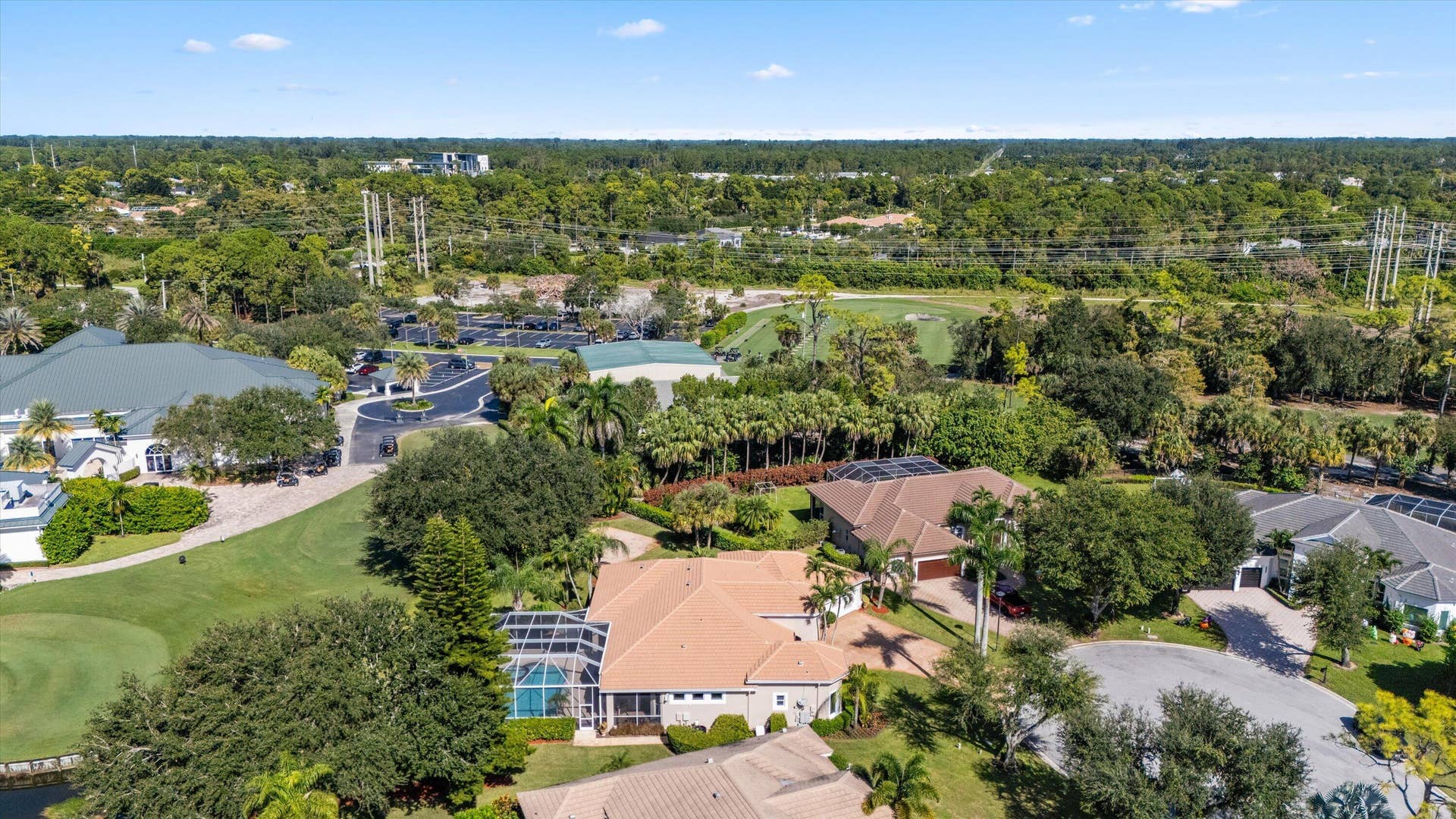 Aerial perspective featuring a residential lot with a screened lanai, a private pool, tile roof construction, and mature landscaping