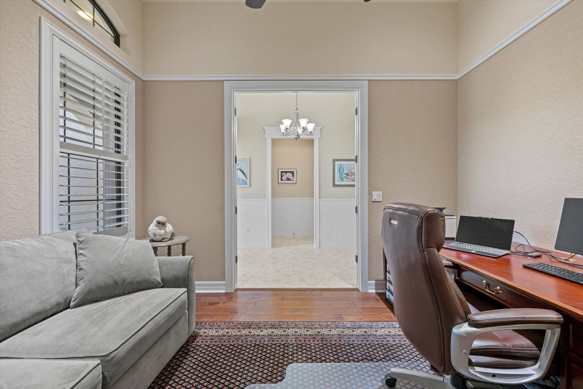 Room featuring high ceilings, wood-finish flooring, crown molding, and a wide doorway with decorative trim