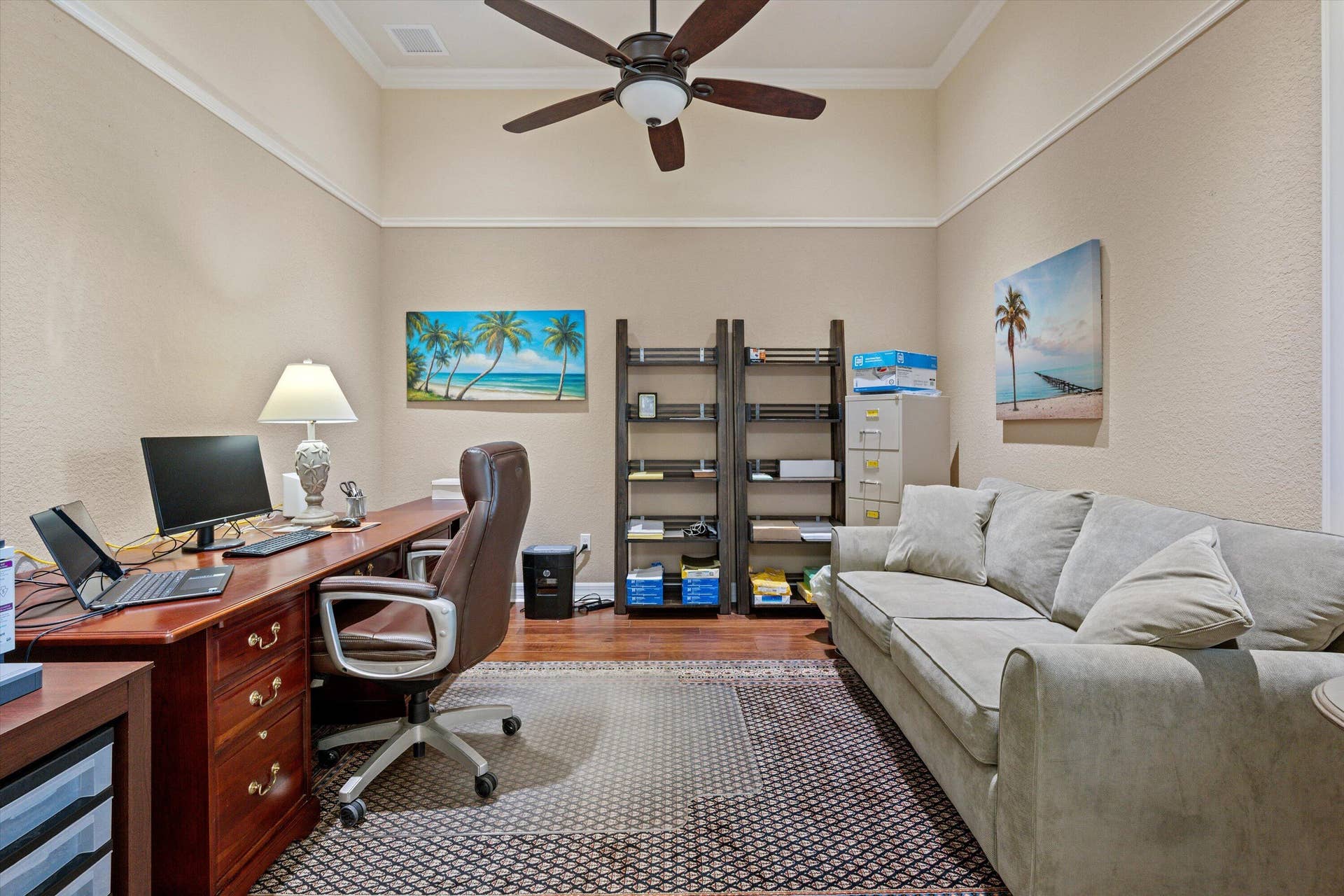 High ceiling featuring crown molding and a central ceiling fan with an integrated light fixture, complemented by wood-finish flooring