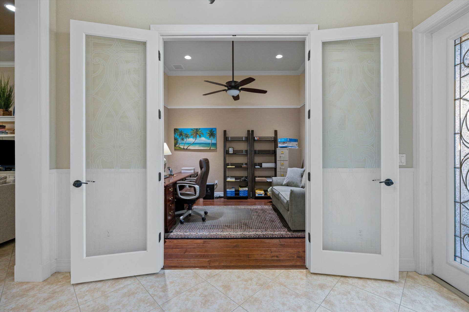French-style double doors featuring frosted glass panels and dark hardware, wood-finish flooring, recessed lighting, and a ceiling fan