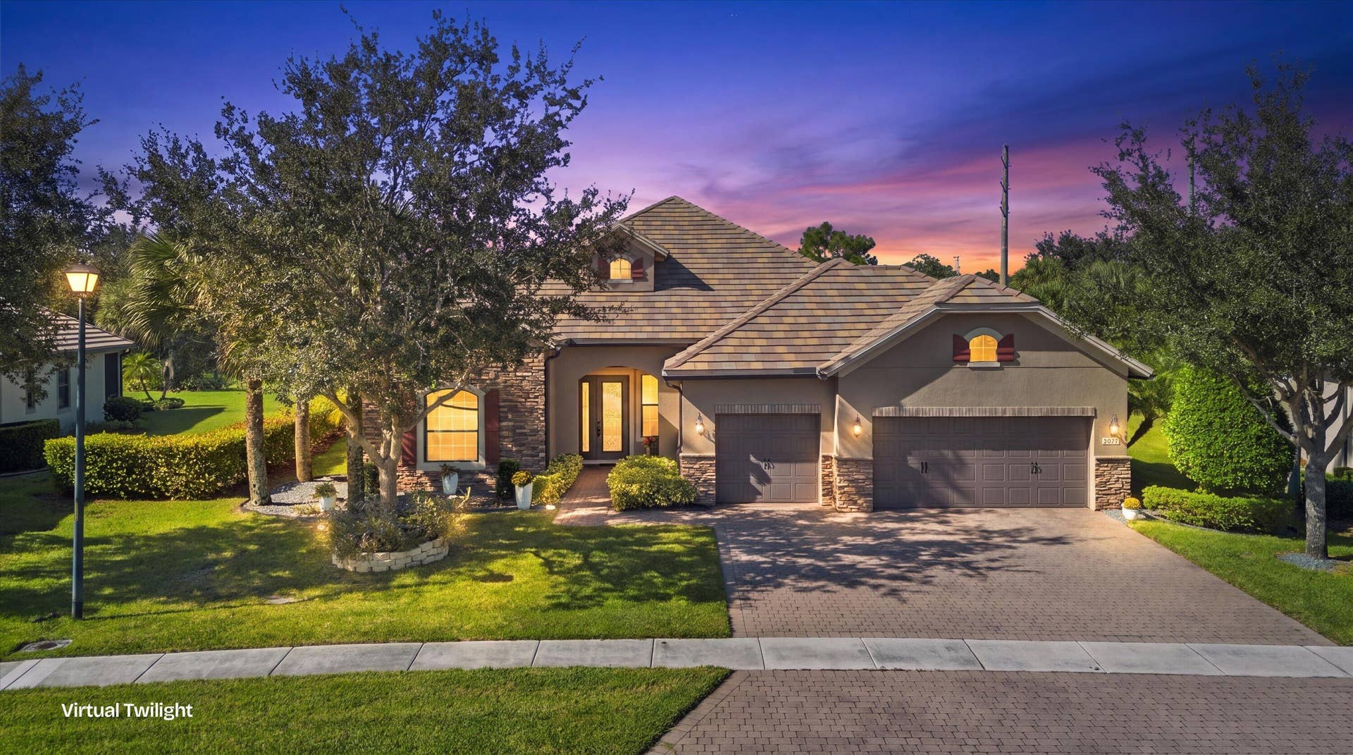 Multi-gabled exterior featuring stone veneer siding, a paved driveway, and a three-car garage