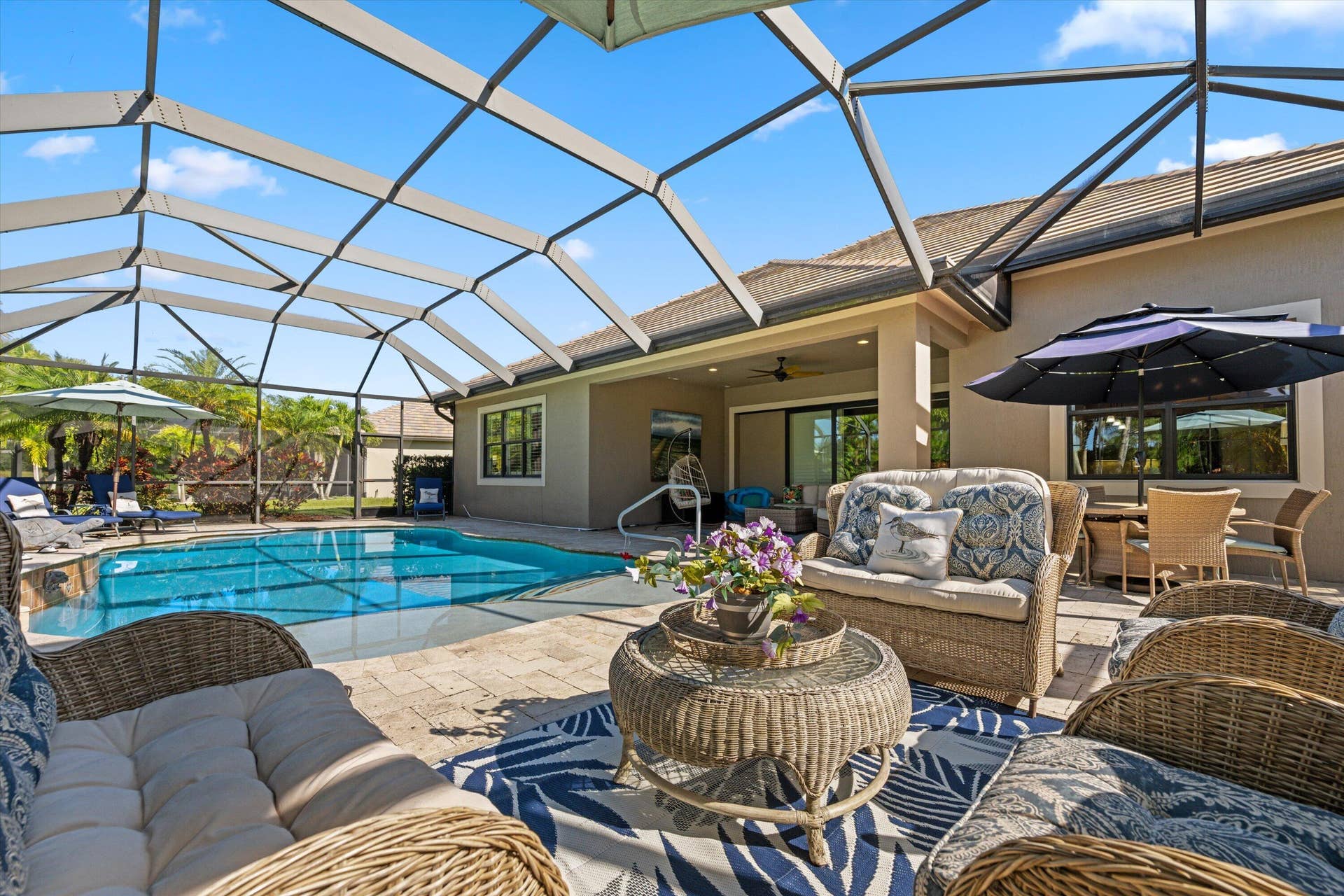 Screened-in patio featuring a swimming pool, stone paver decking, and a covered lanai