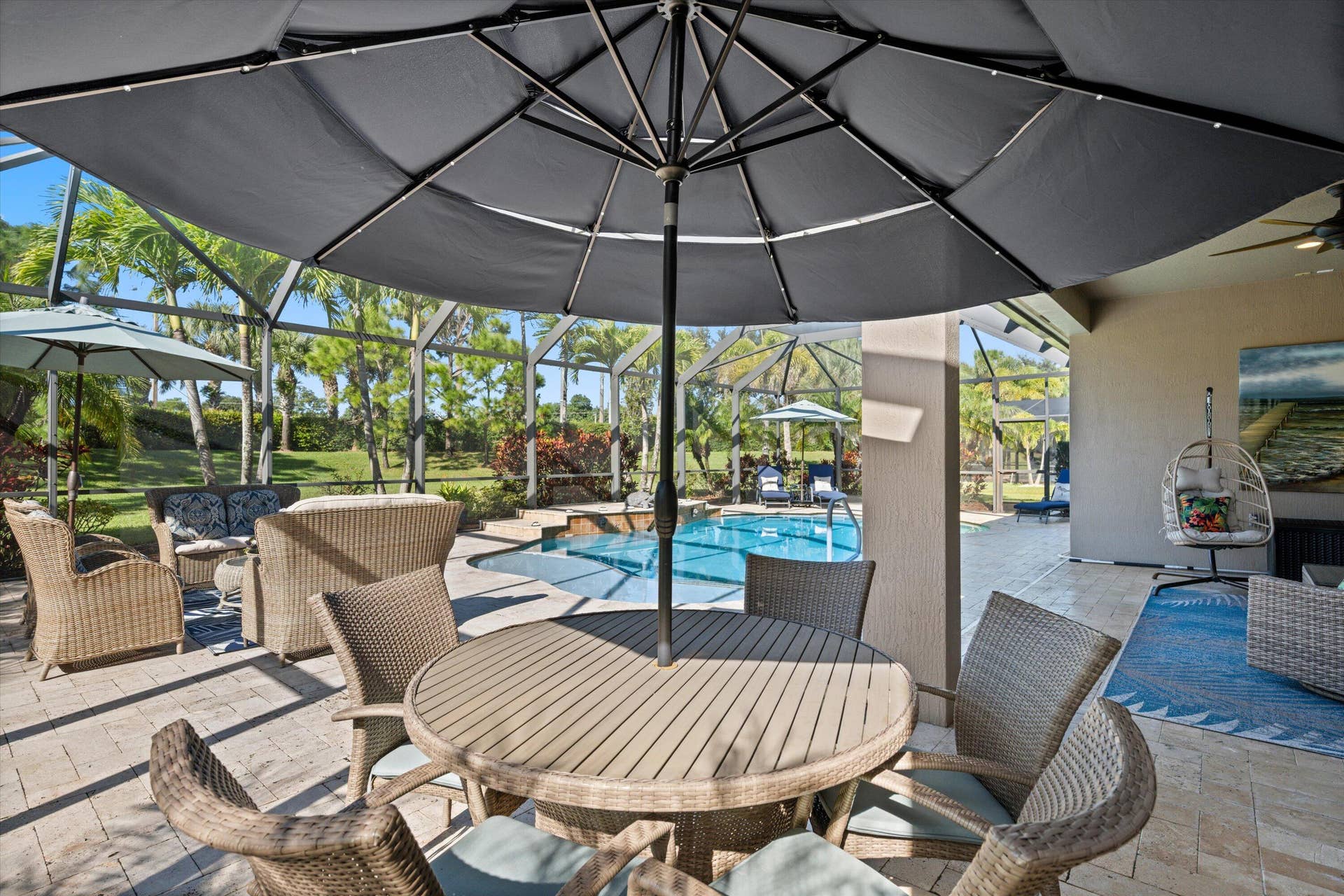 Screened lanai featuring paver flooring, custom pool with built-in spillway, and ceiling fan