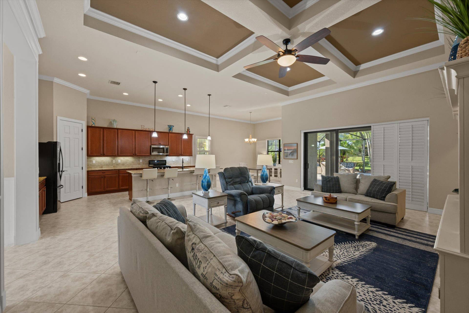 Open-concept interior featuring a coffered ceiling, recessed lighting, tile flooring, and custom cabinetry with an integrated breakfast bar