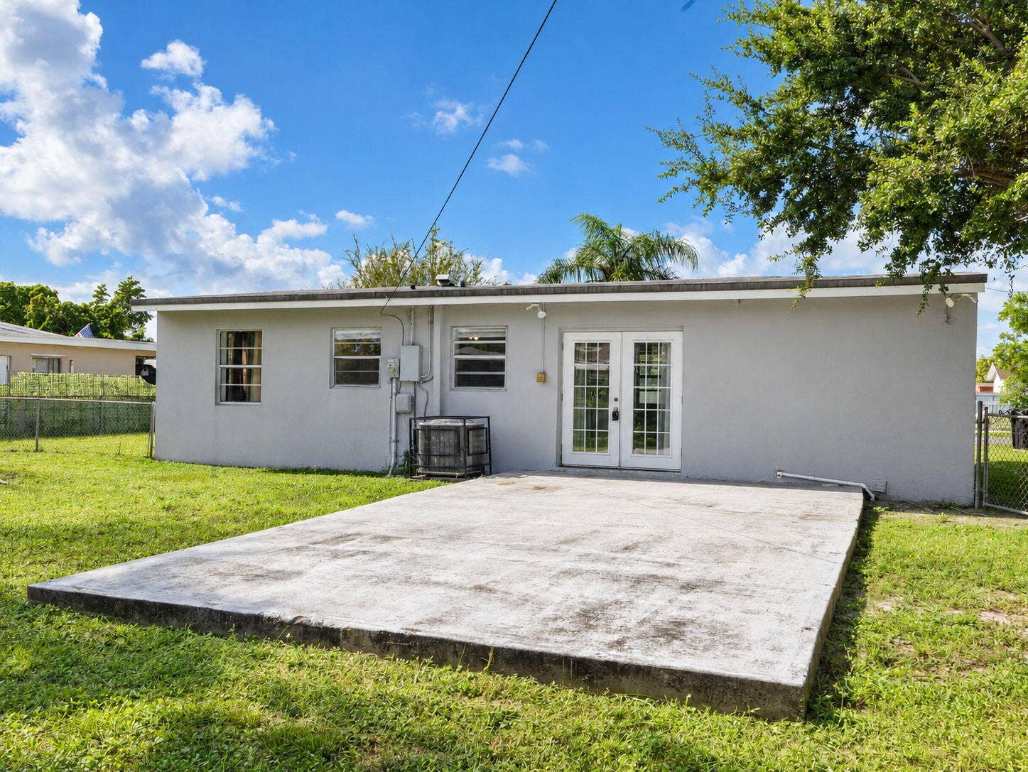 1805 NW 13TH Court, Fort Lauderdale, FL 33311 Rear exterior featuring a concrete patio and a chain-link fenced perimeter