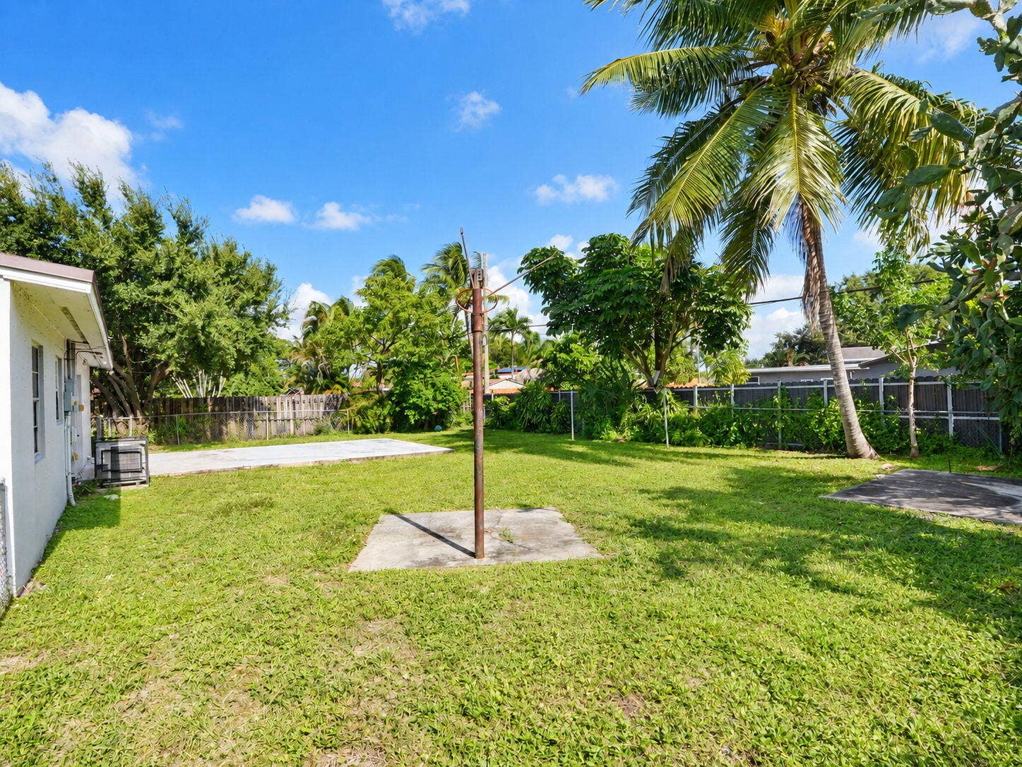 1805 NW 13TH Court, Fort Lauderdale, FL 33311 Backyard space featuring mature palm trees, concrete pads, and perimeter fencing