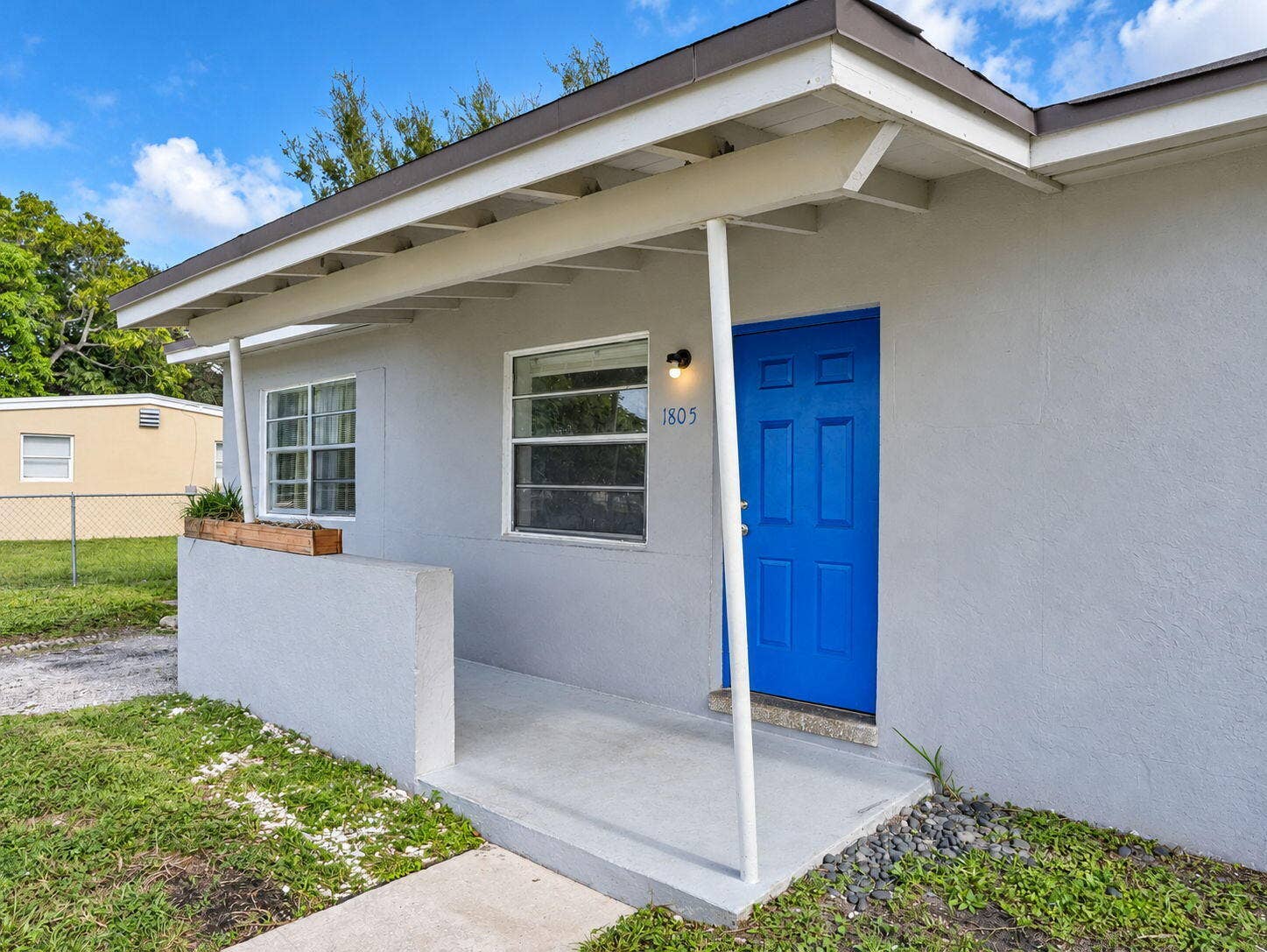 1805 NW 13TH Court, Fort Lauderdale, FL 33311 Exterior featuring a stucco facade, covered porch with a concrete stoop, single-panel blue front door