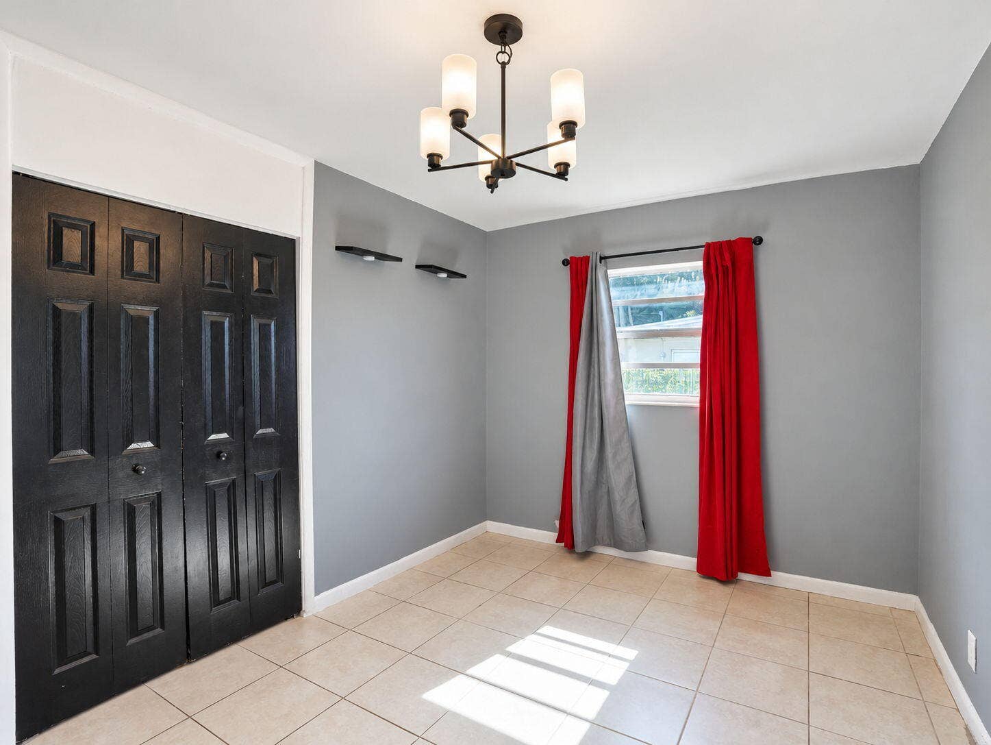 1805 NW 13TH Court, Fort Lauderdale, FL 33311 Neutral-toned tile flooring, four-panel black bi-fold closet doors, multi-arm chandelier with frosted glass shades, and two integrated wall-mounted accent shelves