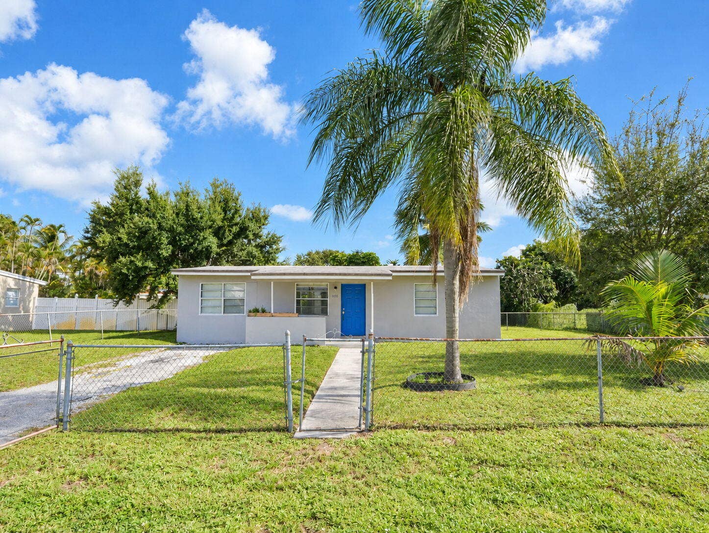 1805 NW 13TH Court, Fort Lauderdale, FL 33311 Single-story exterior featuring a concrete walkway, chain-link perimeter fencing, and mature palm landscaping