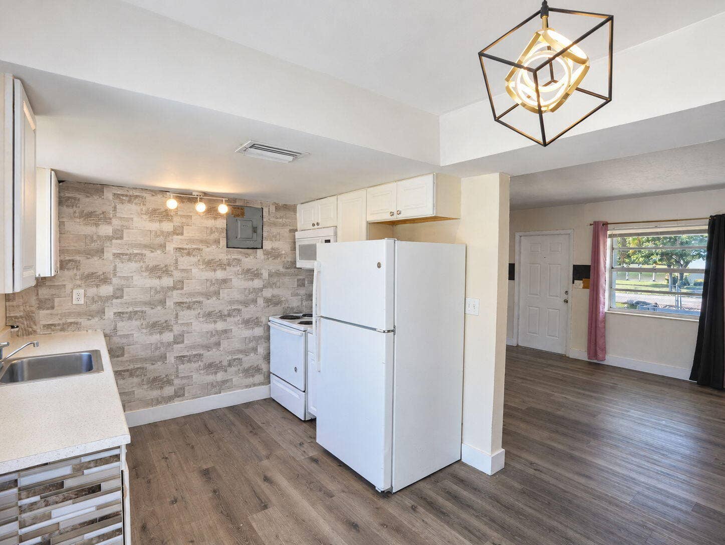 1805 NW 13TH Court, Fort Lauderdale, FL 33311 Kitchen featuring wood-finish flooring, white cabinetry, integrated geometric pendant lighting, and a neutral-toned countertop