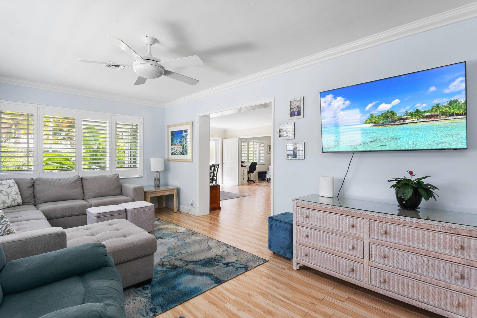 2607 SE 21ST Street, Fort Lauderdale, FL 33316 Living area featuring light-toned wood-finish flooring, white plantation shutters, crown molding, and big picture windows allowing lots of natural light