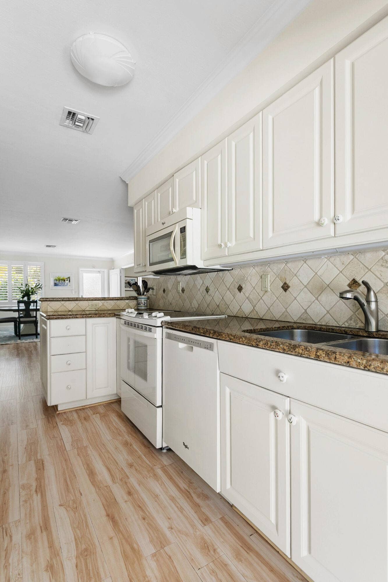 2607 SE 21ST Street, Fort Lauderdale, FL 33316 Kitchen featuring neutral wood cabinetry, stone-finish countertops, diagonal-set tile backsplash, wood-finish flooring, and integrated white appliances