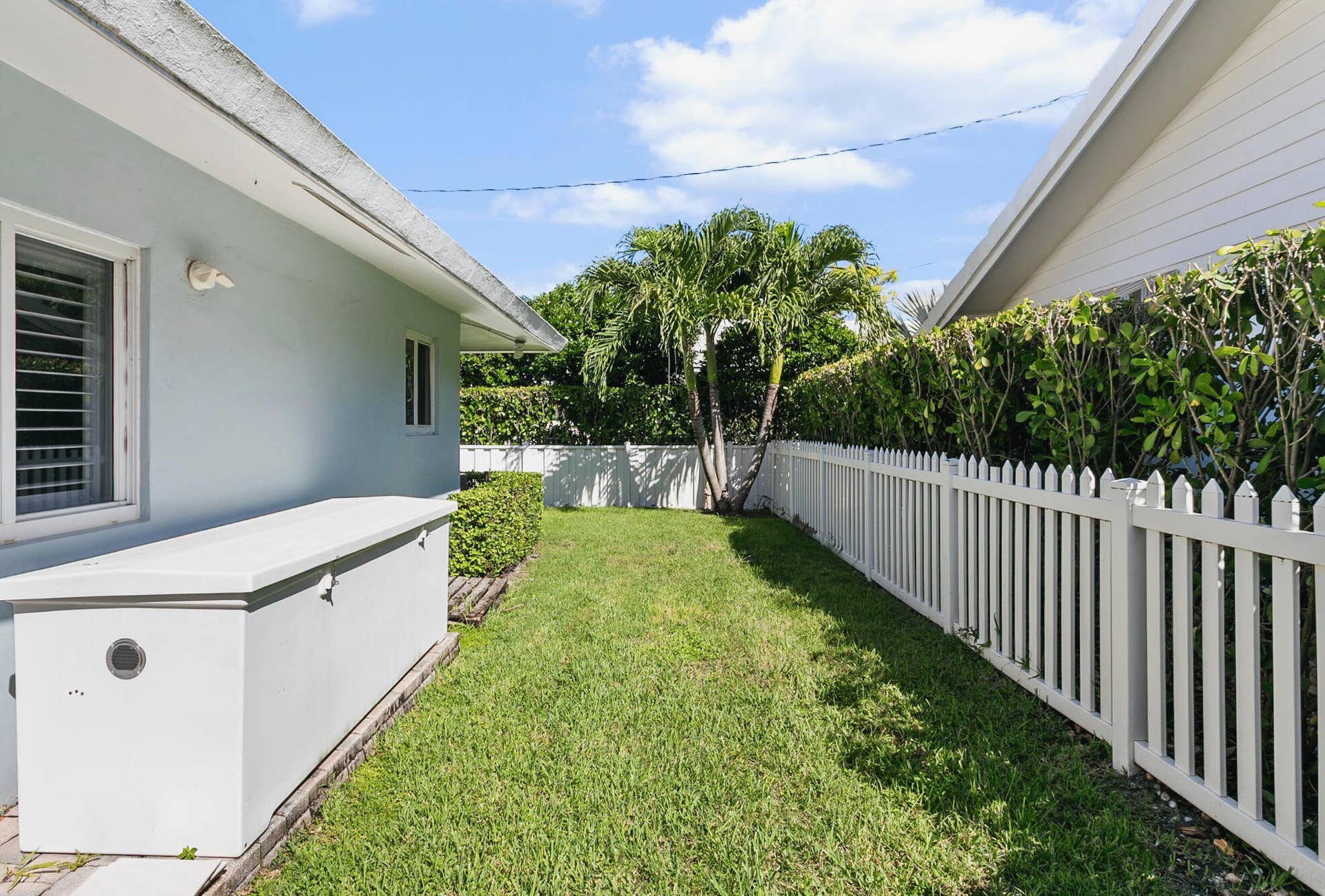 2607 SE 21ST Street, Fort Lauderdale, FL 33316 Side yard featuring a manicured lawn, white picket fencing, structured hedge landscaping. Ideal area for pets to play and roam