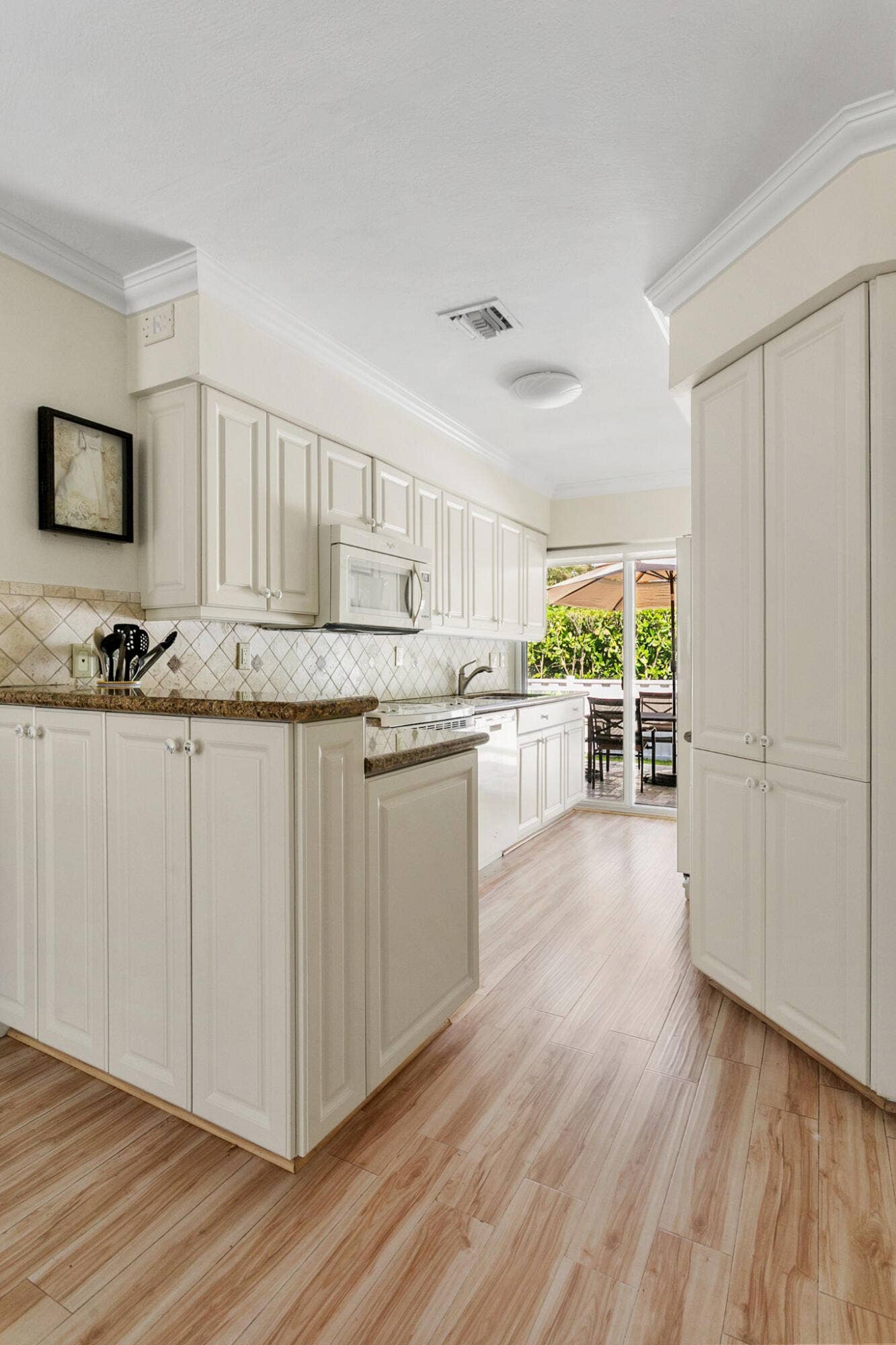 2607 SE 21ST Street, Fort Lauderdale, FL 33316 Kitchen featuring off-white cabinetry, stone-finish countertops, diagonal tile backsplash, and light wood-finish flooring
