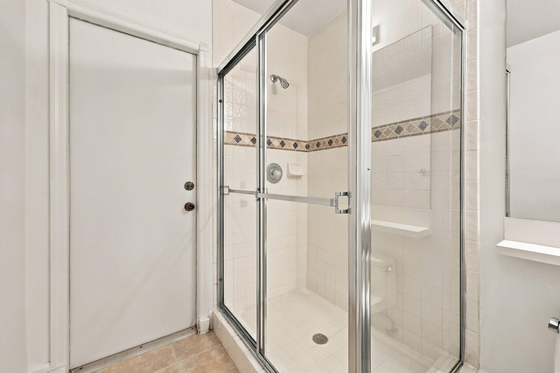 10671 St Thomas Drive, Boca Raton, FL 33498 A convenient main-level guest bathroom featuring a glass-enclosed walk-in shower with decorative tile accents and neutral finishes.